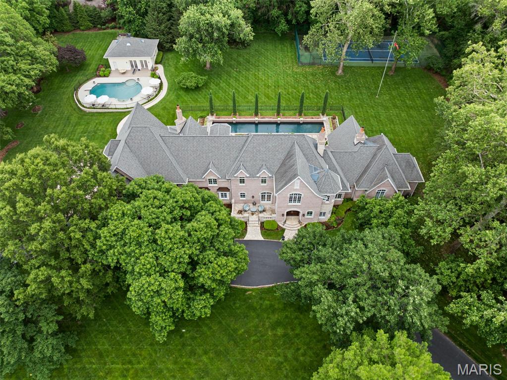 The ultimate in privacy and sophistication, this 2.84 acre estate is tucked quietly in the heart of Ladue adjacent to St Louis Country Club.  With over 12,000 sq ft (7 bed, 8 full and 2 half baths) the main home offers custom high end craftmanship and finishes throughout.  Find soaring ceiling heights on every level, exquisite moldings, rich hardwoods, updated kitchen/hearth room with butler’s pantry/scullery, custom stone wine cellar with tasting rm, theatre and more.  The primary bedrm wing located on the main floor, offers a coffee bar, den access, his/her walk in closets and luxury bath.  Another main floor bedrm is perfect for visiting inlaws.  Four large bedrm suites with walk in closets and a large gym (rec rm) with wet bar and private bath comprise the spacious 2nd floor.  A 5th secondary bedrm suite is found on the 3rd floor.  
The light filled back gallery hall with formal wet bar is the perfect spot to take in the backyard of this property.  Lush landscaping surrounds the main pool with full pool house, a separate lap pool, tennis court, gorgeous gardens and patios perfect for indoor/outdoor living and entertaining.  The scale, quality and location of this estate could not be duplicated for this price in today's market.