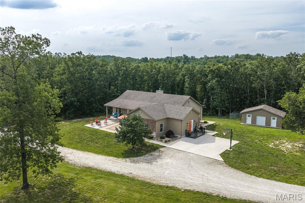 Discover the peace and privacy of your own secluded oasis with this custom-built, one-owner home nestled on 44+/- acres of serene countryside. Hidden from view with no visible neighbors, this tranquil sanctuary is surrounded by nature and accessed by a scenic private driveway, creating a true sense of escape from the everyday. Offering the perfect blend of comfort, recreation, and peaceful country living, this exceptional property invites you to relax, unwind, and enjoy the quiet beauty of your surroundings. The property boasts abundant deer and turkey on the property and many large bass amongst other species in the pond. The home features an open-concept design with vaulted ceilings, Anderson windows, commercial-grade flooring, and quality construction throughout, including glued and screwed subfloors. A 4-foot-wide hallway and staircase provide accessibility and spaciousness. The home offers 3 bedrooms and 3 bathrooms, plus a 4th room that does not qualify as a bedroom. The inviting main living area includes a wood-burning fireplace, while the finished basement features a wood-burning stove for added warmth and charm. The kitchen is designed for both function and style with granite countertops, custom cabinetry, stainless steel Maytag appliances, a large walk-in pantry, and abundant storage. Additional custom touches include barn doors, a bonus pool table room with a custom bar, and zoned HVAC for comfort and efficiency. The outdoor areas raise this property to another level. Enjoy peaceful mornings on the 6-foot-wide covered front porch or entertain family and friends across three separate patios. A 12x18 composite upper deck connects to a large composite pool deck surrounding the 54-inch-deep above-ground pool, creating the perfect setting to relax and spend time with family. The land is beautifully diversified with a stocked pond, natural spring, creek, ATV trails, and open areas for animals and recreation. Equestrian and livestock amenities include a 2-acre electric-fenced horse pasture, a brand-new loafing shed for horses, a 12x20 metal shed with a 60x80 run for goats or other animals, and a chicken coop with a fenced pen. For those needing workspace and storage, the impressive 40x40x15 metal building includes a concrete floor, 15x40 lean-to with a 50-amp RV hookup, 10x40 loft storage area, and dedicated workshop or office space. Additional features include a 15x26 tool shed with dog run and a 50x50x5 chain-link dog run. The property is equipped with a Generac whole-house generator connected to a 500-gallon propane tank, providing peace of mind year-round. The property is serviced by well water and septic. While currently one private estate, the land has already been subdivided by the new owner will have the potential to split further if desired. If you've been searching for a truly secluded property where you can enjoy nature, privacy, recreation, and modern comforts all in one place, this one delivers.