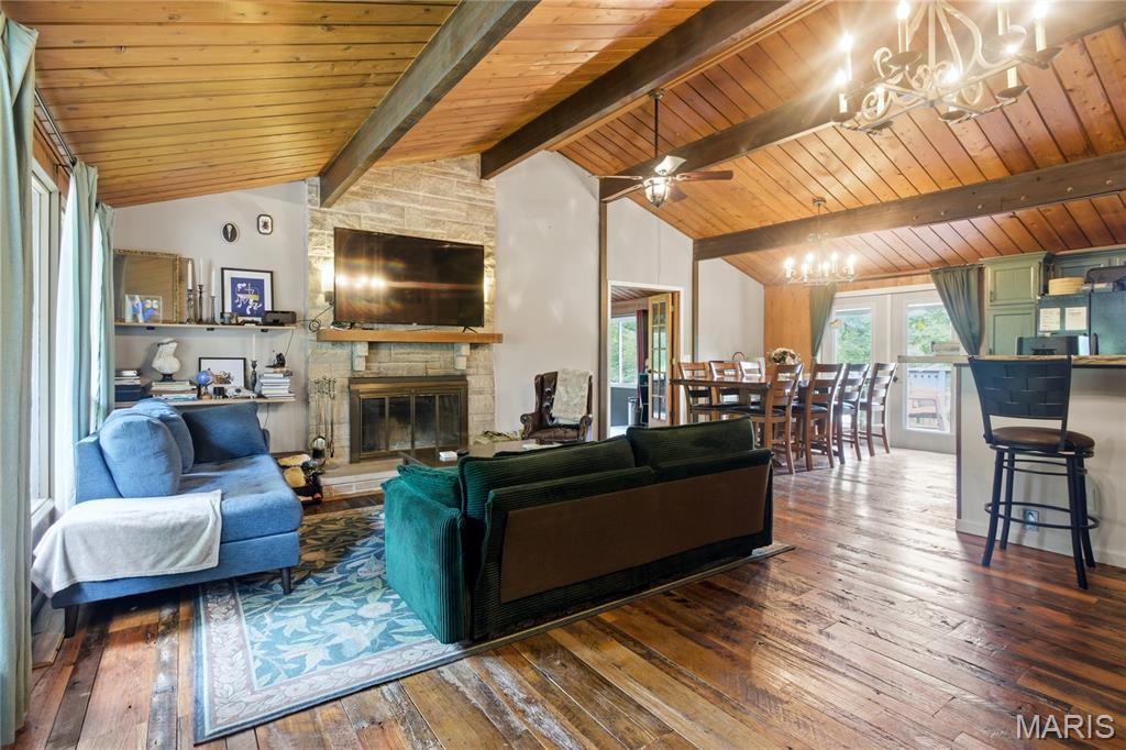 Escape the ordinary without leaving Wildwood. 

Tucked among mature trees on more than four private acres, this one-of-a-kind retreat offers the peace and seclusion of a mountain getaway just minutes from everyday conveniences. If you've been searching for privacy, character, and a home that doesn't look like every other listing, you've found it.

Inside, warm wood ceilings, exposed beams, and a dramatic stone fireplace create an inviting lodge-inspired atmosphere that immediately feels like home. The open living and dining areas are designed for gathering, while the custom main-floor bar adds a memorable space for entertaining friends, hosting holidays, or simply unwinding after a long day.

Some rooms are simply part of the floor plan. This one becomes part of your life. Just off the living and dining rooms, a beautifully designed gathering space creates the kind of place people naturally gravitate toward. Whether it's craft cocktails with friends, a favorite bottle of wine shared over conversation, pizzas after soccer practice, holiday appetizers spread across the counter, a spirited game-day watch party, or family lingering long after dinner, it's a space that adapts to every season of life and every reason to gather.

The finished walkout lower level expands the living space, offering flexibility for a family room, recreation area, home office, fitness space, or guest accommodations. Large windows throughout the home frame peaceful wooded views that change beautifully with every season.

Step outside to a spacious deck where morning coffee comes with birdsong instead of backyard neighbors. A fenced yard provides room for pets or play, while the surrounding woods create the privacy and natural beauty that are becoming increasingly difficult to find.

Character may capture your attention, but thoughtful updates provide lasting peace of mind, including a new roof in 2025, dual zoned HVAC systems installed in 2018 and 2019, and new basement carpet in 2026.

This isn't simply a house on acreage. It's a home for buyers who value privacy, nature, entertaining, and the feeling of coming home to their own personal retreat every day.