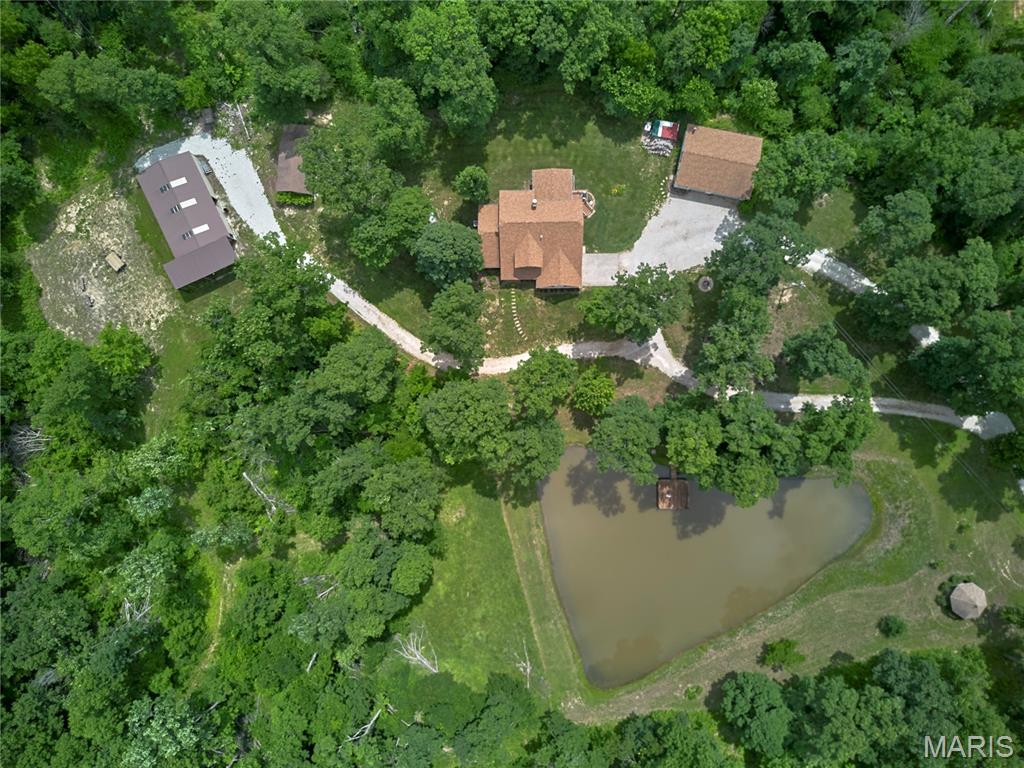 The perfect package, privacy galore, and an original owner who has lovingly maintained this incredible homestead! Nestled on 20 beautiful acres just off blacktop roads, this custom-built 2,500+ sq.ft. 1.5 story home with multiple outbuildings, private pond and spring on the property is truly a rare find. The home features 3 Bedrooms, 2.5 Baths, Main Floor Primary Suite, Main Floor Laundry, and an open floor plan designed to capture the peaceful views of nature from every angle. The Great Room showcases soaring atrium windows and a see-through fireplace flowing into the Breakfast Room and Kitchen, creating the perfect space for gathering and entertaining. A separate Dining Room offers additional flexibility for hosting, office space, or family needs. The spacious Kitchen includes abundant cabinetry, buffet area, pantry, and access to the 12x17 Sunroom/Deck overlooking the private setting, pond, and surrounding acreage. Upstairs offers Bedrooms 2 & 3, a full bath, and loft area that could easily serve as a 4th Bedroom, office, or recreation space. Outside, the property continues to impress with a 30x40 detached garage featuring insulation, concrete floors, woodburning stove, exterior door, and double garage doors; a 30x50 Morton building with lean-to; and a 24x16 finished wood shop with concrete floors and garage door. Enjoy peaceful evenings at the pond with floating dock, gazebo, and nothing around you but nature. Additional features include Anderson windows, newer roof on the home and detached garage, softener system, new well pump and motor in 2023, electric furnace, and Hardy Stove capable of heating both the home and water. A truly one-of-a-kind property offering privacy, functionality, and country living at its finest. Showings expected to begin Thursday, June 4th.