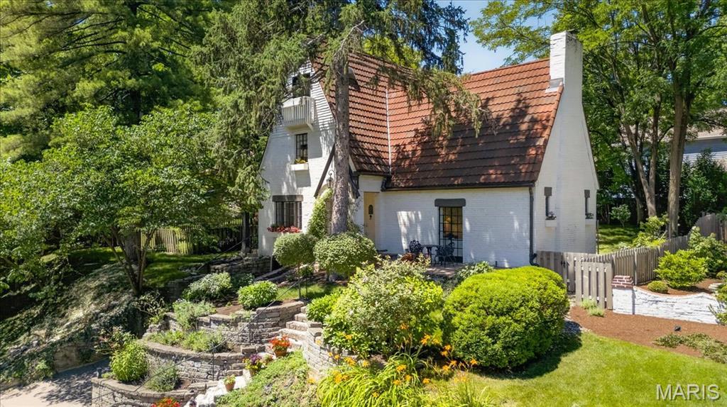 Tucked along a quiet lane in the heart of Webster Groves, this enchanting English cottage feels as though it has been lifted from the pages of a storybook. Rich in character and architectural distinction, 149 Valley Road welcomes you with a charming stone porch - the perfect place to savor a morning coffee as the sun rises. Throughout the home, remarkable details showcase a level of craftsmanship rarely found today, from exposed beam ceilings to intricate millwork and architectural accents that lend warmth at every turn. The dramatic vaulted living room with hand-hewn beams and a stunning fireplace makes an unforgettable first impression and anchors the space with timeless elegance. The beautifully updated kitchen is a masterpiece in its own right, boasting custom floor-to-ceiling gallery shelves, an eight-burner range with double ovens, and a commercial-grade hood. Blending charm, functionality, and exceptional attention to detail, this kitchen makes both everyday living and entertaining enjoyable. Upstairs, the primary suite extends to a full third-floor dressing room and renovated bath complete with a one-of-a-kind shower and marble sink, creating a unique sanctuary, while a second bedroom and bath provide comfortable accommodations for family and friends. The lower level offers flexible living space well-suited for a rec room, workout space, or home office. Outside, the magic continues. Designed as a private garden oasis, the grounds feature a distinctive black-and-white harlequin-patterned dipping pool, a cascading waterfall, and a serene koi pond. Whether hosting friends, enjoying quiet evenings under the stars, or simply taking in the beauty of the surroundings, this outdoor space delivers! Rarely does a property combine such architectural charm, modern livability, and an idyllic setting—all just moments from the shops, restaurants, and vibrant community of downtown Webster Groves.