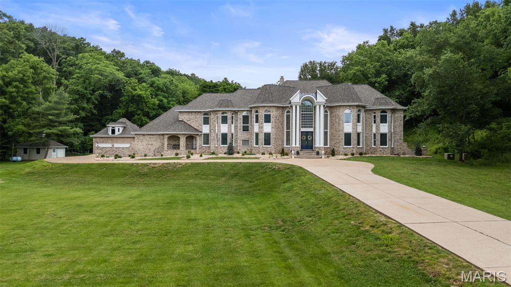 Coming soon! Some places are seen. Others are experienced. Ten private acres. One extraordinary estate. Rare 10-Acre Classic American Estate in the Heart of Wildwood - offering unparalleled privacy, acreage, lake views, room for multigenerational living and an exceptional lifestyle. Welcome to this beautiful estate nestled on 10 private acres in one of St. Louis County's most prestigious estate corridors. A sweeping approach and grand columned entrance create an unforgettable first impression, complemented by manicured grounds and timeless curb appeal. Exceptional craftsmanship and designed on a grand scale, this all-brick residence offers over 7,300 square feet of total living space. Highlights include a dramatic two-story foyer with a sweeping staircase, formal living room with fireplace and wall of windows, elegant dining room, richly paneled executive office offering work-from-home flexibility, six bedrooms, six full bathrooms, a five-car garage with room for car collectors, workshop space, and endless outdoor recreation opportunities. The chef's kitchen is both functional and inviting, featuring a large center island, peninsula seating, custom white cabinetry, natural stone countertops and backsplash, and stainless steel appliances. Adjacent to the kitchen are a planning desk, convenient back staircase providing direct access to the primary suite, and a sun-filled breakfast room overlooking the grounds. Step outside to the spacious screened porch and adjoining patio, where peaceful views of the private wooded setting create the perfect backdrop for relaxing or entertaining. The main level also features an expansive family and game room with custom built-ins and wet bar with beverage center, a private guest bedroom adjacent to a main floor full bathroom, a mirrored fitness room with adjoining full bath, and a generously sized laundry room. The luxurious primary suite serves as a private retreat with a coffered ceiling, sitting area, two french doors walks out to a large terrace with sweeping views of the property, oversized walk-in closet, and a stunning, fully renovated spa-inspired bath featuring dual vanities, an oversized walk-in shower with dual shower heads and rain shower, separate soaking tub, an upstairs laundry and abundant natural light. Additional amenities include a partially finished walk-out lower level offering endless possibilities for recreation or additional living space. Rarely does a property combine this level of acreage, privacy, timeless architecture, and refined estate living in the heart of Wildwood in the Rockwood School District. Private enough to escape, close enough for everyday life. Some homes are built—this one is remembered.