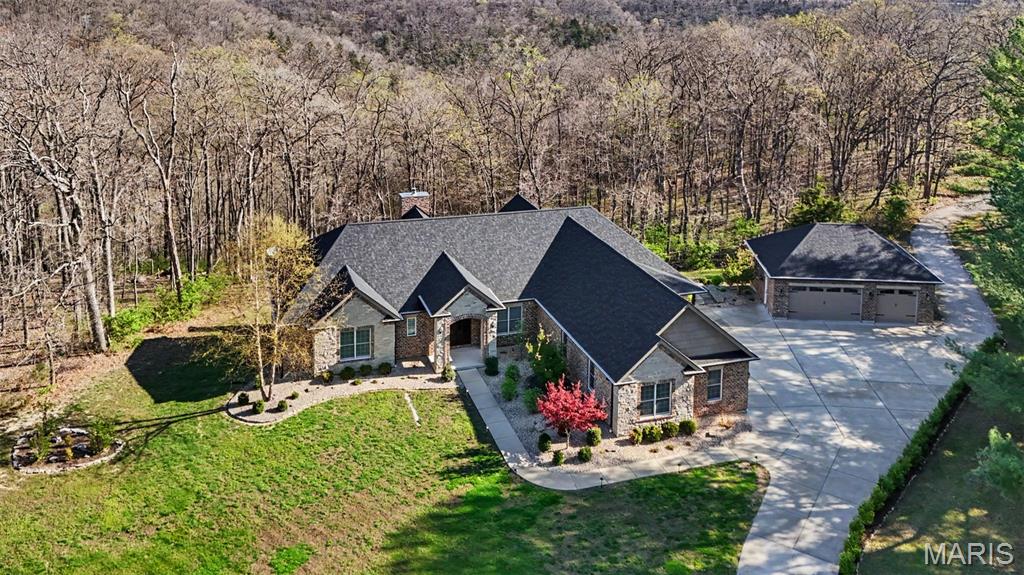 Experience the ultimate in privacy and natural beauty with this stunning custom waterfront property nestled on 25.5+/- mostly wooded acres with frontage on the serene waters of Callaway Valley Lake. Crafted with exceptional attention to detail, this one-of-a-kind property showcases rich woodwork and impeccable craftsmanship throughout. Highlighted by a grand wood-paneled ceiling with softly arched beams, and a floor to ceiling stone fireplace that lend warmth and architectural elegance to the main living space. At the heart of the home lies an open, elegant luxury kitchen that is sure to impress with custom cabinetry, premium appliances, and generous prep space, making it ideal for both everyday living and entertaining in style. Hop in the side by side and head to the lake to enjoy your own private boat dock, perfect for fishing, kayaking, sunset cruises, or simply soaking in the peaceful lakeside setting. This land is ideal for hunting, hiking, and exploring, offering year-round outdoor adventure in your own backyard. Additional features include a total of 7 garage spaces, a versatile detached 3 car garage, a large chicken coop,  and charming Barn with loft space and concrete floors adding both functionality and character to this exceptional property. All of this is set within a peaceful, wooded landscape that feels worlds away—yet is just minutes from  New Melle, Wentzville and Defiance, Missouri. ATTN: option to just purchase additional acreage available at 50k/acre.