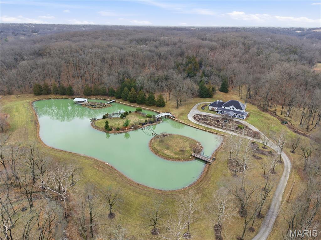 Welcome to your Dream Retreat in Columbia, Missouri!

Nestled on 26 breathtaking acres, this one-of-a-kind property offers the perfect balance of luxury living and incredible outdoor recreation. The land features a beautifully stocked private lake complete with islands and charming bridges, creating a stunning centerpiece that feels like your own private resort. The property is also loaded with deer and turkey, making it an exceptional retreat for wildlife lovers and outdoor enthusiasts.

The 7,500± square foot custom home has been meticulously cared for and is filled with high-end features throughout. From the moment you step inside the granite entryway, you’ll appreciate the craftsmanship and attention to detail, including hand-scraped teak floors, a stunning curved staircase, and two fireplaces. The home offers four spacious bedrooms and five bathrooms, along with a quiet study, large office space, abundant storage, and an attached three-car garage.

The fantastic kitchen is built for both everyday living and entertaining, featuring a Wolf gas stove, high-end appliances, a hidden pantry, and generous storage space throughout. Just off the main living area, the sunroom provides the perfect place to relax and watch the wildlife, overlooking the incredible scenery this property has to offer.
The luxurious master suite includes a spa-like bathroom equipped with heated floors, TV, coffee maker, and refrigerator, as well as a large walk in closet. 

The finished basement is designed for entertaining, featuring a spacious entertainment area along with a bar and small kitchen, making it the ideal place to host guests, watch the big game, or unwind after a long day.
Outside, the property also includes a large two-story outbuilding with potential living quarters, providing endless possibilities for guests, a workshop, or additional storage. 

This rare 26 +/- acre estate truly offers the best of both worlds — a private paradise retreat with incredible scenery, wildlife, and recreation, all located just 7 miles from downtown Columbia. Opportunities like this are incredibly rare!