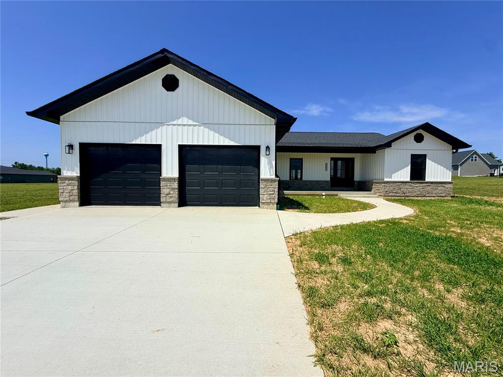New construction with timeless curb appeal and quality finishes throughout! This beautifully designed ranch-style home offers 1,894 square feet of thoughtfully planned living space featuring 3 bedrooms, 2 baths, and a highly desirable split-bedroom floor plan. From the moment you arrive, you'll appreciate the striking exterior showcasing natural stone wainscoting, crisp white vertical siding, black accents, and an inviting covered front porch that creates a warm first impression. Step inside to discover an open-concept layout highlighted by a vaulted ceiling that enhances the spacious living room, dining area, and kitchen. The kitchen is sure to be the heart of the home, featuring beautiful stained wood cabinetry, quartz countertops, a tiled backsplash, and a stunning black center island that provides both style and functionality. The split-bedroom design offers privacy for the primary suite while two additional bedrooms share a conveniently located hall bath. Main-level laundry adds to the home's everyday convenience. Retreat to the spacious primary suite complete with dual closets and a luxurious private bath featuring a double sink vanity and an enormous tiled walk-in shower. The oversized two-car garage provides ample room for vehicles, storage, and hobbies. Need more space? The full unfinished basement offers endless possibilities for future expansion and is already roughed in for a future bathroom. Outside, you'll enjoy a covered back porch overlooking the level yard—an ideal setting for entertaining guests, grilling, or simply relaxing at the end of the day.