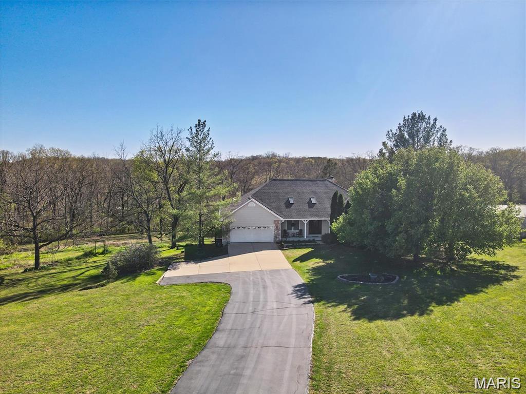Welcome to your own private retreat! Nestled on 4.16 picturesque acres in the sought-after Hillsboro School District, this beautifully maintained custom ranch offers 3,752 sq. ft. of finished living space, 4 bedrooms, 4 full baths, and 1 half bath with room for everyone. Fresh new carpeting adds a move-in ready touch, while the open floor plan, soaring cathedral ceilings, and skylight fill the home with natural light. The spacious great room features a stunning floor-to-ceiling stone wood-burning fireplace, while the chef's kitchen is complete with granite countertops, stainless steel appliances, center island, walk-in pantry, and abundant cabinetry. Enjoy your morning coffee in the sunroom overlooking the peaceful backyard or unwind on the expansive deck surrounded by nature. The oversized primary suite offers a spa-like bath with whirlpool tub, separate shower, dual vanities, and walk-in closet. Each additional bedroom has access to its own full bathroom, providing exceptional comfort and privacy. The finished walkout lower level provides additional living space with a large media/rec room, fourth bedroom, full bath, office, and endless possibilities for entertaining. Outside you'll find a beautiful patio, wooded privacy, abundant wildlife, and a 30' x 40' outbuilding with water and 100-amp electric service—ideal for hobbies, equipment, or a workshop. Recent updates include a new roof (2024), oversized rain gutters, and new carpet, giving buyers peace of mind. Plus, this property is USDA eligible for qualified buyers. If you're searching for privacy, space, and quality craftsmanship just minutes from town, this is the one you've been waiting for!