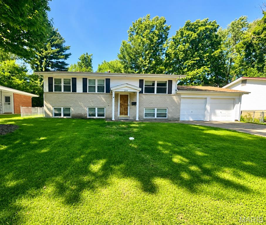This freshly painted, well-maintained 4-bedroom, 1.5-bath home offers a versatile layout and inviting living spaces both inside and out. The main level features wood flooring, a living room with abundant natural light and three bedrooms, including a primary bedroom with a private half bath. The large eat-in kitchen has stainless steel appliances, ample cabinet and counter space, and opens directly to the patio overlooking the level, fully fenced backyard—perfect for pets, entertaining, or simply relaxing outdoors. The walkout lower level offers a fourth bedroom, additional living space, storage, and direct access to the backyard. An attached two-car garage with a workspace area in the back adds everyday convenience. Located near shopping, dining, parks, and major roadways. With fresh paint, flexible living spaces, and a great backyard, this home is ready for its next owner!