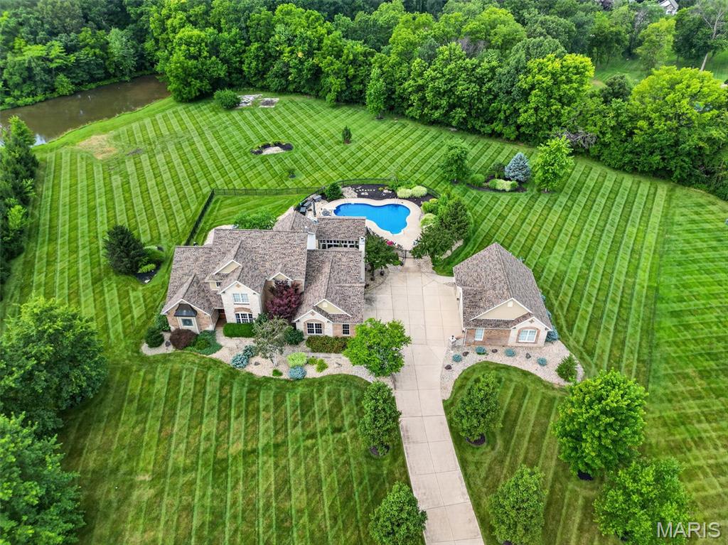 Luxury 1.5 story home in a private cul-de-sac located in a gated community minutes from everything on a private 3.01 acre tree lined lot with a 5 car gar (6 w/lift), inground salt water pool, and an 18x20 pool house w/full Kitchen. You will love the long driveway as the home sits back off the road with views of a pond. Enjoy a picturesque approach, brick/stone façade, O/S side entry gar, detached gar and lawn sprinklers with this manicured, landscaped lawn. Home has approx. 6,000 finished sq/ft/ with a main level primary suite and 3 bedrooms upstairs. Seller just recently finished the LL with a stunning bar and added an egress window, so you could easily add other bedrooms in the lower level. There are also 6 BA (4+2), that includes the full bath in the 2nd garage that is perfect for everyone using the pool. The 2 story Entry opens to the formal dining room and the great room with high ceilings and Andersen Low E windows with remote control window shades, 4 FP, 9 ft ceilings, brazillian cherry hardwood t/o a large portion of the main level, huge window at the Kitchen sink overlooking the pool and fountain, solid surf c-tops, Viking appl, huge island, hearth room w/bay and coffered ceiling, main floor laundry w/cab-sink-ice maker. The MAIN FLOOR PRIM, Lux Primary Bath, 2 W/I closets, 2 Hi-efficiency HVAC, 2 HWH, new AC (Aug 2024)and water softener. The LL was just professionally finished with approx. 2200 sq/ft with an added egress window, a huge bar, game room, rec room, family room, tons of storage and a half bath.  Upstairs has 3 BD, one en-suite and 2 w/ J & J bath along with W/I closets. The attached gar is O/S (29’2Wx 22’5D). The detached gar is spectacular (28’5Dx29W) w/tall doors (18x8/7x8), car lift, compressor w/2 tanks, 50 AMP serv for RV needs, pull down steps and full bath. The 33,500 gal, heated pool with brand new heater (see updates) comes w/hard cover. WOW! Additional Rooms: Sun Room. Other improvements seller has done recently include: New furnace
Fenced in separate area in backyard for pets
New pool heater
New water heater in detached garage
Lots of landscaping and tree tear outs/clean up
Surround sound by pool
Surround sound in finished basement
New ceiling fan in pool house
Privacy trees planted right side of pool
New garage door openers on detached garage all 3 doors
Electric window black out shades in primary bedroom
Electric shade laundry room
Updated kitchen faucet
New hood fan in pool house above grill
New screens in pool house
New outdoor GFI outlets around pool
Fountain re painted and pressure washed
Stained wood post on pool house
Finished the entire LL professionally