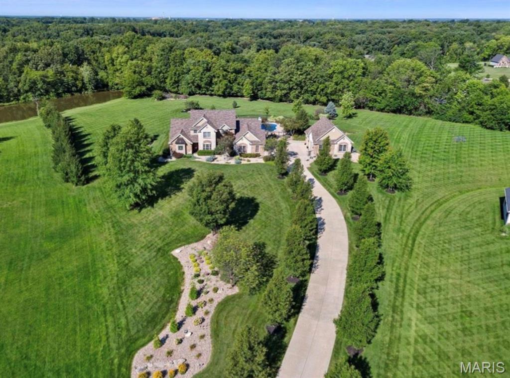 Luxury 1.5 story home in a private cul-de-sac located in a gated community minutes from everything on a private 3.01 acre tree lined lot with a 5 car gar (6 w/lift), inground salt water pool, and an 18x20 pool house w/full Kitchen. You will love the long driveway as the home sits back off the road with views of a pond. Enjoy a picturesque approach, brick/stone façade, O/S side entry gar, detached gar and lawn sprinklers with this manicured, landscaped lawn. Home has approx. 6,000 finished sq/ft/ with a main level primary suite and 3 bedrooms upstairs. Seller just recently finished the LL with a stunning bar and added an egress window, so you could easily add other bedrooms in the lower level. There are also 6 BA (4+2), that includes the full bath in the 2nd garage that is perfect for everyone using the pool. The 2 story Entry opens to the formal dining room and the great room with high ceilings and Andersen Low E windows with remote control window shades, 4 FP, 9 ft ceilings, brazillian cherry hardwood t/o a large portion of the main level, huge window at the Kitchen sink overlooking the pool and fountain, solid surf c-tops, Viking appl, huge island, hearth room w/bay and coffered ceiling, main floor laundry w/cab-sink-ice maker. The MAIN FLOOR PRIM, Lux Primary Bath, 2 W/I closets, 2 Hi-efficiency HVAC, 2 HWH, new AC (Aug 2024)and water softener. The LL was just professionally finished with approx. 2200 sq/ft with an added egress window, a huge bar, game room, rec room, family room, tons of storage and a half bath.  Upstairs has 3 BD, one en-suite and 2 w/ J & J bath along with W/I closets. The attached gar is O/S (29’2Wx 22’5D). The detached gar is spectacular (28’5Dx29W) w/tall doors (18x8/7x8), car lift, compressor w/2 tanks, 50 AMP serv for RV needs, pull down steps and full bath. The 33,500 gal, heated pool with brand new heater (see updates) comes w/hard cover. WOW! Additional Rooms: Sun Room. Other improvements seller has done recently include: New furnace
Fenced in separate area in backyard for pets
New pool heater
New water heater in detached garage
Lots of landscaping and tree tear outs/clean up
Surround sound by pool
Surround sound in finished basement
New ceiling fan in pool house
Privacy trees planted right side of pool
New garage door openers on detached garage all 3 doors
Electric window black out shades in primary bedroom
Electric shade laundry room
Updated kitchen faucet
New hood fan in pool house above grill
New screens in pool house
New outdoor GFI outlets around pool
Fountain re painted and pressure washed
Stained wood post on pool house
Finished the entire LL professionally