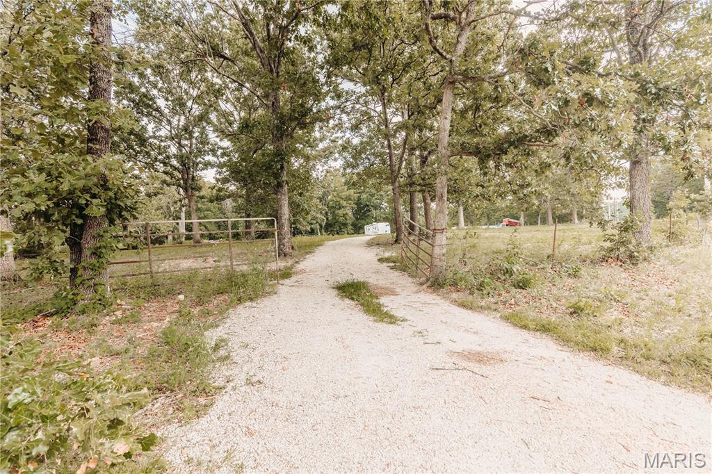 More photos coming soon! On approximately 28 acres of gently rolling pasture, mature woods, and a stocked pond, this unique property offers the perfect blend of privacy, recreation, and convenience just a short drive from town. Built in 2022, the one-level metal-construction shouse is designed for easy maintenance and comfortable country living. The open-concept floor plan is highlighted by a cozy wood-burning stove, antique kitchen cabinetry that adds warmth and character, and easy access to the mudroom, attached garage, and front screened porch. The spacious 25' x 8' screened-in porch provides the perfect place to enjoy morning coffee, evening sunsets, or peaceful views overlooking the stocked pond while watching horses graze, wildlife roam, and the changing seasons unfold. The thoughtfully designed bathroom features an antique vanity and offers convenient access from the primary bedroom, main living area, and laundry room. The attached 1000 square foot shop/garage provides ample room for vehicles, equipment, recreational toys, or hobbies, complete with built-in shelving for additional storage. Just outside, a concrete pad with RV hookup creates additional opportunities for guests, travel trailers, or future expansion. Whether you're looking to establish a homestead, create a weekend getaway, enjoy exceptional hunting and wildlife watching, operate a short-term rental or Airbnb, or simply experience peaceful country living with room to roam, this property offers possibilities. With wooded acreage, open pasture, a horse corral, and a stocked pond, there is plenty of space for livestock, recreation, gardening, or outdoor adventures while still enjoying convenient access to nearby amenities.