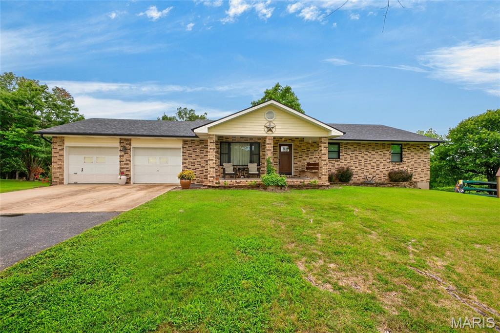 Tucked away near the end of a quiet road, this charming brick home offers the perfect blend of peaceful country living and everyday convenience. Relax on the welcoming covered front porch with your morning coffee before stepping inside to a spacious living room filled with warmth and comfort. The beautifully appointed kitchen features granite countertops, stainless steel appliances, a gas range, and generous dining space perfect for gathering with family and friends.

The thoughtfully designed main level includes a convenient laundry room complete with counter for clothes folding, hanging bars, and extra storage. Two secondary bedrooms, a full bath with a tub/shower combination, and a private primary suite complete the main floor.
Downstairs, you'll discover even more living space with a large family room, a fourth bedroom featuring a walk-in closet, an additional full bathroom, a dedicated office, plus abundant storage and utility space. The home also includes an attached two car garage, along with ample driveway parking.

Step outside to enjoy your own private retreat. An oversized deck overlooks the picturesque backyard, where you'll find a pergola-covered entertaining area, cozy fire pit, storage shed, raised garden beds, and a charming greenhouse ready for your next growing season. Situated on 5.25 +/- acres just outside the city limits, this property offers the serenity of country living without sacrificing convenience. Enjoy easy access to I-44, downtown Waynesville, and Fort Leonard Wood, making this exceptional property the perfect place to call home.
