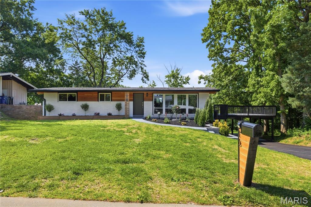 Completely reimagined and renovated from top to bottom, this stunning mid-century modern inspired home offers the perfect blend of architectural style, functional living space, and high-end designer finishes throughout. Situated on a beautiful lot with mature trees and incredible outdoor living areas, this turnkey property delivers a rare combination of character, space, and modern convenience. The main level features 3 spacious bedrooms and 2 full bathrooms, thoughtfully designed with an open and airy feel filled with natural light. The heart of the home showcases clean architectural lines, oversized windows, warm cedar accents, designer lighting, and a seamless indoor-outdoor connection. The beautifully updated kitchen flows effortlessly into the living and dining spaces, creating an ideal layout for both everyday living and entertaining. The finished lower level significantly expands the home’s living space and includes 2 additional bedrooms, a full bathroom, and a bonus room perfectly suited for a private office, workout room, playroom, or flex space. The lower level also features expansive sliding glass doors that flood the space with natural light and create an inviting extension to the outdoor entertaining areas. One of the home’s standout features is the incredible custom wet bar area complete with granite countertops, dual beverage refrigerators, custom cabinetry, and dramatic black accent walls that create a true luxury entertaining experience. Every bathroom has been beautifully updated with modern finishes, including a spa-inspired walk-in shower with designer tilework and sleek matte black fixtures. Step outside to enjoy the massive elevated deck overlooking the backyard, offering endless possibilities for entertaining, relaxing, or enjoying peaceful views. The exterior has been completely transformed with fresh landscaping, modern retaining walls, updated siding and paint, warm wood architectural details, and exceptional curb appeal that immediately sets the home apart. From the striking mid-century modern aesthetic to the thoughtfully curated finishes throughout, every detail of this renovation was carefully considered. A rare opportunity to own a fully renovated designer home with 5 bedrooms, 3 full bathrooms, flexible living space, and unforgettable indoor-outdoor entertaining areas. Truly move-in ready and unlike anything else on the market.