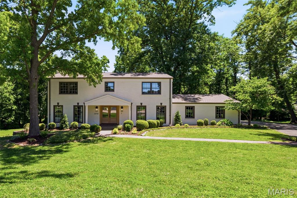 Welcome to 19 Sackston Woods Lane — a fully reimagined designer estate tucked away on a private, wooded one-acre lot in the heart of Creve Coeur. Beyond the columned portico and custom wood-and-glass double entry, over 4,000 square feet of curated living unfolds with master craftsmanship at every turn. A paneled study with French doors sits just off the foyer, while warm luxury plank flooring leads into a showstopping chef’s kitchen: professional-grade stainless appliances, quartzite countertops with a full-height stone backsplash, two-tone custom cabinetry, a generous center island with seating, and a walk-in butler’s pantry with sink and dishwasher. A custom coffee and beverage bar with reeded-glass cabinetry, floating shelves, and a wine cooler adds the perfect entertainer’s touch. The vaulted great room is the heart of the home — soaring wood-beamed ceilings, skylights, and walls of windows framing the trees, anchored by a fireplace wrapped in floor-to-ceiling millwork and flowing into a sun-drenched dining room beneath dramatic arched windows. The main-level primary suite is a private retreat with its own fireplace, designer wall paneling, a spa-inspired bath with double vanity and a custom arched-tile shower with a thermostatic pressure system, and a walk-in closet. A main-level mudroom off the garage doubles as a second laundry room, and the garage is fitted with an EV charger. Upstairs offers four additional bedrooms — including a mother-in-law suite with private bath — plus a hall bath, second-floor laundry, and custom closets throughout. The finished walk-out lower level adds expansive recreation space, a dry bar with dual beverage coolers, and a full bath. Step outside to a sprawling multi-level deck with a covered gazebo overlooking the rolling, tree-lined grounds. Five bedrooms, five baths, and a level of design you simply have to see in person.