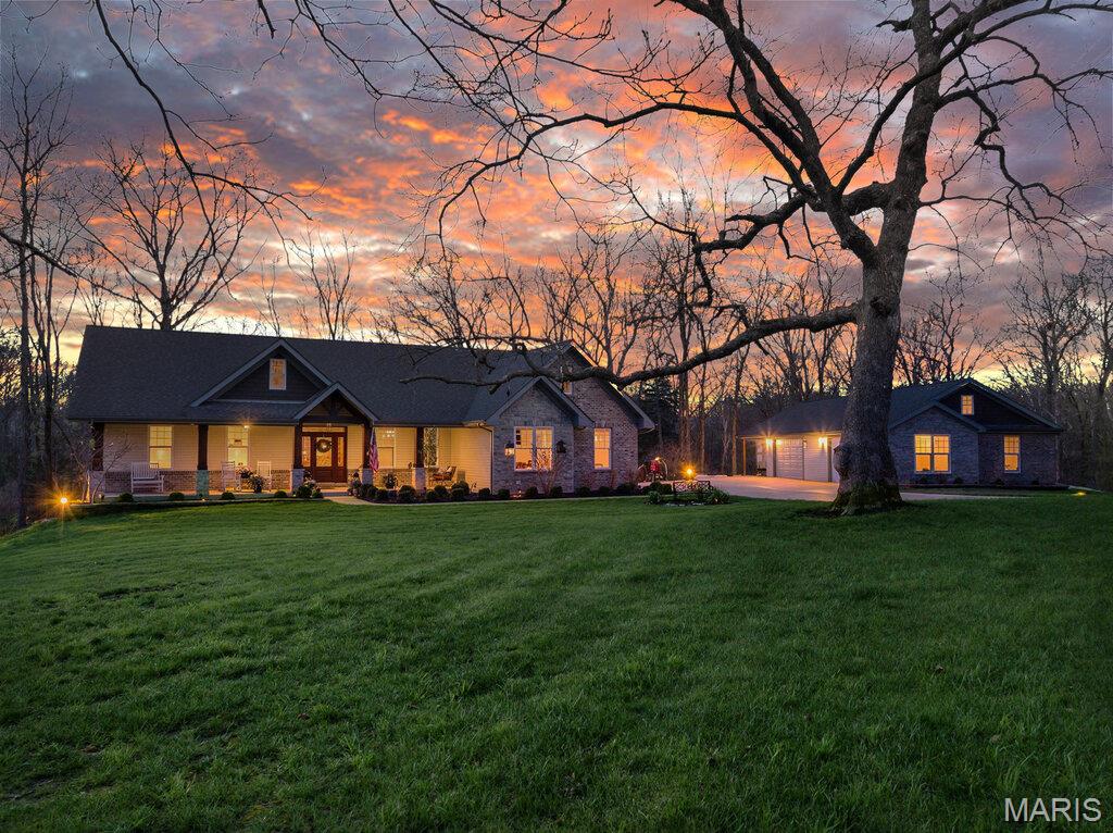 Discover unparalleled luxury and versatility in this custom Craftsman style estate, perfectly situated on a 4.5 acre private and wooded lot.  From the moment you arrive the striking architectural lines and manicured landscaping signal a home of exceptional quality.  The heart of the home is a magnificent open concept great room merging seamlessly with a gourmet kitchen.  Natural light pours through windows flanking a floor to ceiling stone fireplace.  The kitchen itself is a showstopper boasting custom white cabinetry, quartz countertops, stainless steel appliances with double wall ovens, a stylish subway tile backsplash and an expansive center island with storage that is perfect for casual mornings or grand entertaining.  Adjacent to the kitchen is the breakfast room and hearth with coffered ceilings that open directly to a serene screened in porch.  The custom wood built-in shelving in the hearth room surround a  stone propane fireplace.  Don't forget about the home's Formal Dining room with views of the front lawn!  Retreat to the primary suite, a true sanctuary featuring a spa-inspired ensuite and His and Hers walk-in closets.  Indulge in the oversized walk in tile shower, deep soaking tub under a picturesque garden window and massive dual sink vanity with a dedicated makeup station.  Two additional main floor bedrooms, a full and half bath offer comfort and style for family or guests.  The finished walk out lower level doubles your living space featuring a secondary family room with a stone fireplace and built in library style shelving.  A media room, 4th bedroom and full bath can also be found in the lower level.  While here visit the 13x30 workshop that has a full garage door facing the rear of the home that opens to a huge concrete patio.  The thoughtfully designed lower level still allows for ample storage space.  For the hobbyist or car enthusiast the garage space is unmatched.  In addition to the 3 car 23x36 attached garage the estate features a massive detached garage and a covered lean-to.  Complete with a main floor laundry room this estate offers every modern convenience in a tranquil park like setting.