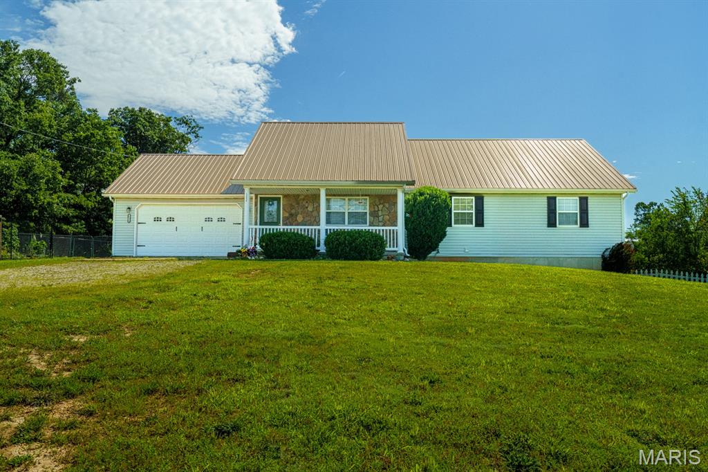 Would you like to experience living in a neighborhood surrounded by the splendor of the Mark Twain National Forest? 
Check out this move-in ready beautifully maintained ranch-style home in Plato. Built in 2007, this single-family residence perfectly balances colonial curb appeal with exceptional outdoor living. A welcoming front porch invites you into a spacious, well-designed layout featuring 4 bedrooms, 2 full bathrooms & a finished basement. The primary bedroom offers an attached bathroom with 2 walk in closets. The fourth bedroom located in the basement, includes another walk in closet for ample storage. Other highlights include an attached garage with direct interior access. HVAC has a transferable NINE YEAR Warranty! The thermostat has optional smart capabilities. Once you step outside on to the back deck you’ll find a 6ft multi gated fenced backyard. To the north of the property is an additional fenced garden area including a green house for all your seedlings & garden supplies. The gated garden is currently growing a variety of sunflowers, perennials, sage & wildflowers. There is still plenty of room for raised bed gardens & much more. Schedule your private viewing today!