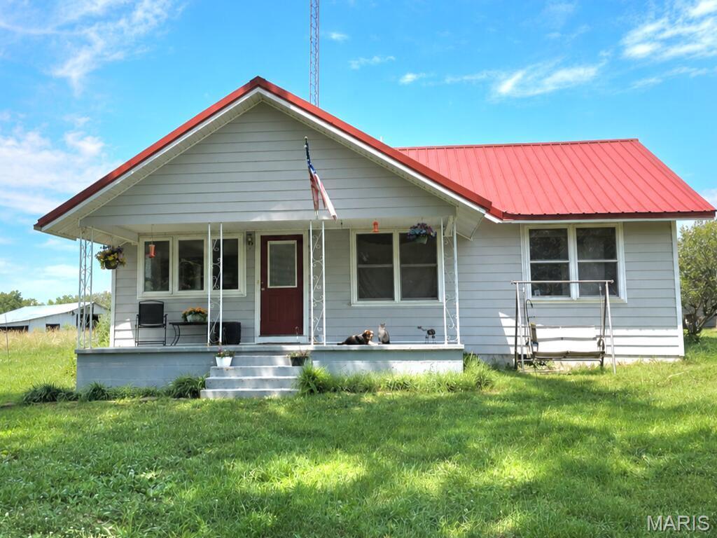 Nestled on scenic acreage, this charming 1 bedroom, 1 bath home offers the perfect blend of peaceful and rural living! Country kitchen with wood cabinetry, ample counterspace and pantry closet. The living room features a propane fireplace and plenty of natural light, creating a warm and inviting space. Primary bedroom with walk-in closet and adjoining bathroom featuring double vanity, separate shower and jetted tub. Upstairs loft that offers additional space or storage options. Detached garage with parking area and workshop. Shop building with concrete floors, electric, heating and cooling. Storage building and a greenhouse providing the ideal space for gardening enthusiasts to grow year-round. Wet-weather creek and plenty of space for recreation, hobby farming, or simply enjoying the outdoors. Conveniently located a few minutes outside of Houston on 4.7 acres!