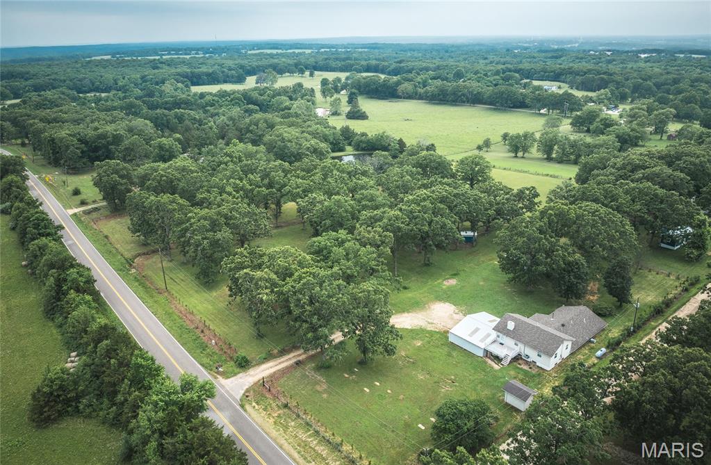 Welcome to this 5 bedroom, 3 full bathroom home set on 6.32 beautiful acres! This spacious home offers over 2,500 square feet of living space and a flexible floor plan perfect for a variety of lifestyles. The main level features 3 bedrooms, 2 full bathrooms, a spacious living room with a wood-burning stove, a full kitchen with a pantry area, a recreation room, multiple storage and bonus rooms, and convenient washer and dryer hookups. The primary suite offers a beautifully tiled bathroom complete with a no step walk-in shower. The upper level provides an excellent extension of living space with 2 additional bedrooms, a full bathroom, a nice kitchen featuring a cooktop, built-in oven, and refrigerator, a comfortable sitting area, a bright sunroom, separate water heater, and additional washer and dryer hookups. With separate exterior access and its own living areas, the layout offers exceptional flexibility for multi-generational living, guests, or extended family. Outside, you’ll find everything needed to start your own homestead. The property includes a 27X38 metal carport with metal trusses, multiple storage sheds, a  lean-to with electric, a chicken coop, garden beds, and dedicated garden space ready for planting. Sellers had a brand new private well installed in 2025! Beautiful landscaping enhances the setting while the acreage provides room for livestock, recreation, or simply enjoying the peaceful surroundings. This property combines rural charm with practical amenities. Whether you’re looking for a hobby farm, homestead, or simply more space to enjoy country living, this property is ready to welcome you home.