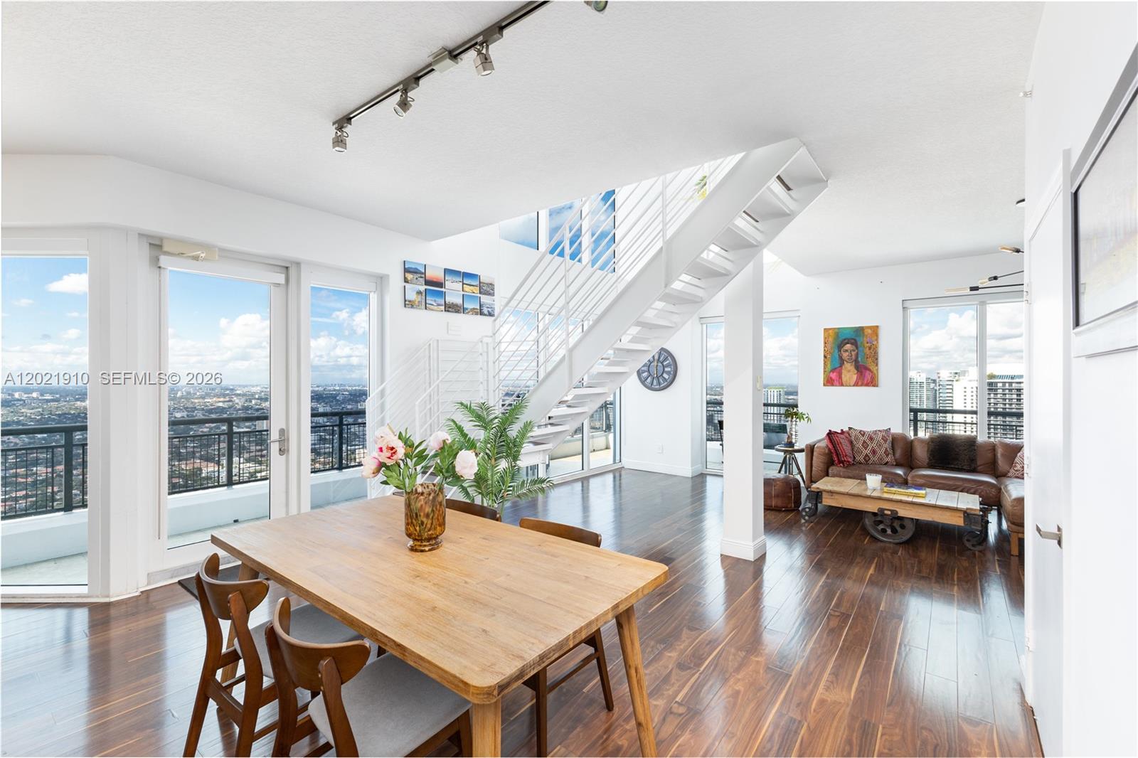 Stunning two-story loft residence at Infinity at Brickell with breathtaking wraparound views of the Miami skyline and Biscayne Bay. This rare corner unit offers exceptional privacy and a peaceful atmosphere.
Enjoy unobstructed year-round sunset views and the constantly evolving Miami skyline from multiple private balcony access points.

Dramatic double-height ceilings and expansive floor-to-ceiling windows throughout the residence flood the home with natural light, creating a bright and airy living experience from sunrise to sunset. The open-concept first floor seamlessly connects the kitchen, dining, and living areas, making the space ideal for entertaining while fully embracing the spectacular skyline and sunset views.

Upstairs, the spacious primary suite features generous closet space and a spa-inspired en-suite bathroom with dual vanities, soaking tub, and separate shower. The versatile second bedroom is perfect for guests, a home office, or additional flex space.