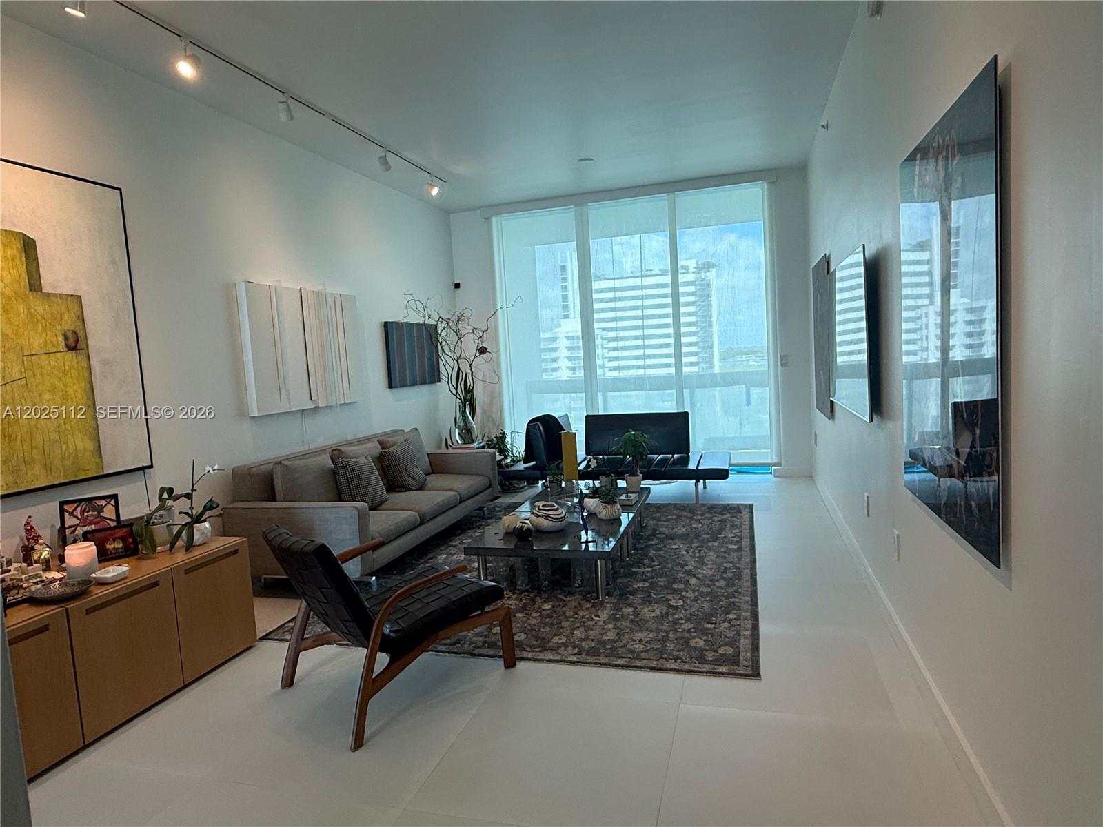 Beautifully curated and thoughtfully evolved residence at Eloquence on the Bay, located in the heart of North Bay Village — one of Miami’s fastest-evolving waterfront destinations, surrounded by water and experiencing major ultra high-end development and long-term investment growth.

Widely recognized as one of the safest waterfront communities in Miami, North Bay Village offers its own dedicated police department, including both land and marine patrol services, providing an exceptional sense of privacy, security, and quality of life.

This sophisticated 2-bedroom + den, 3-bathroom residence blends art, architecture, and design into a truly unique living experience. Over time, the residence has been continuously refined and upgraded with carefully selected design interventions, materials, lighting, and custom details that elevate both functionality and aesthetics.

The current open-concept den was intentionally designed to expand the social and entertaining areas, though it can easily be enclosed and converted into a third en-suite bedroom with its own private bathroom.

The apartment features two oversized balconies with breathtaking bay and skyline views, creating a seamless indoor-outdoor lifestyle. From sunrise reflections over the water to dramatic sunset skies across Miami, the views become part of the residence itself. Outdoor furnishings include iconic pieces by Richard Schultz, carefully selected and proportioned specifically for the terraces to complement the architecture and flow of the home.

One of the residence’s most striking features is its seamless matte white flooring, creating an almost gallery-like sensation — reminiscent of walking across ice — enhancing the natural light and giving the interiors a clean, floating, contemporary atmosphere throughout.

Thoughtfully curated for both design lovers and art collectors, the home features gallery-style lighting, designer fixtures, custom-built closet interiors, pocket doors for improved spatial flow and functionality, electric shades, and carefully selected finishes throughout. The residence reflects a refined contemporary aesthetic with strong architectural and artistic sensibility while remaining exceptionally well maintained.

A permanent sculptural intervention by contemporary artist Stefan Bruggeman, conceived as part of the residence’s visual identity, remains with the property. An additional artwork by renowned contemporary artist Lisu Vega — recognized for museum-related interventions and exhibitions — may also be available separately and is negotiable.

Select furnishings, including designer pieces by Minotti, as well as outdoor furnishings, may remain and are negotiable as part of the sale, offering the possibility of acquiring a fully curated turnkey residence.

The kitchen combines clean modern lines with premium finishes, while the overall residence delivers a rare blend of contemporary waterfront living, curated interiors, and artistic identity.

Residents enjoy resort-style amenities including marina access, waterfront pool, fitness center, tennis court, half basketball court, and additional recreational spaces. The unit also includes two assigned parking spaces.

Additionally, the building is currently undergoing significant modernization and capital improvements, offering future owners the opportunity to enjoy a substantially renewed waterfront property in one of Miami’s most promising bayfront communities.

A rare opportunity to acquire one of the most uniquely curated and design-forward residences within the building — where contemporary design, art, lifestyle, security, and investment potential come together effortlessly.

Everything shown in the photographs is negotiable… except the dog.