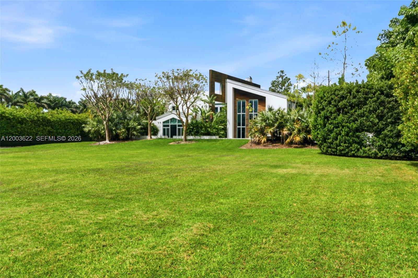 Experience unparalleled modern luxury in this spectacular split plan 6,355-square-foot architectural masterpiece set on a sprawling 2.46-acre private estate in Redland. Designed for the most discerning buyer, this stunning compound features a main residence and secondary structures seamlessly connected by elegant breezeways and lush tropical landscaping. The striking contemporary facade, characterized by crisp white lines, natural wood accents, and expansive oversized windows, sets the tone for the exceptional design found throughout. 

Step inside to discover a breathtaking two-story great room anchored by a dramatic floor-to-ceiling concrete fireplace and an open-tread floating staircase with sleek cable railing. The open floor plan is bathed in natural light, highlighting the high ceilings, modern pendant lighting, and premium finishes. Entertain effortlessly in the custom industrial-chic bar area, complete with a live-edge wood counter, or utilize the dedicated professional production studio space, perfect for creatives or home-based businesses. 

The outdoor living spaces rival a five-star resort. A pristine geometric swimming pool is surrounded by manicured turf and stepping-stone pathways, leading to a massive thatched-roof tiki pavilion equipped with built-in seating and an outdoor television. Multiple covered terraces, two second-floor balconies overlooking the grounds, and a magnificent paver courtyard driveway complete this extraordinary offering.