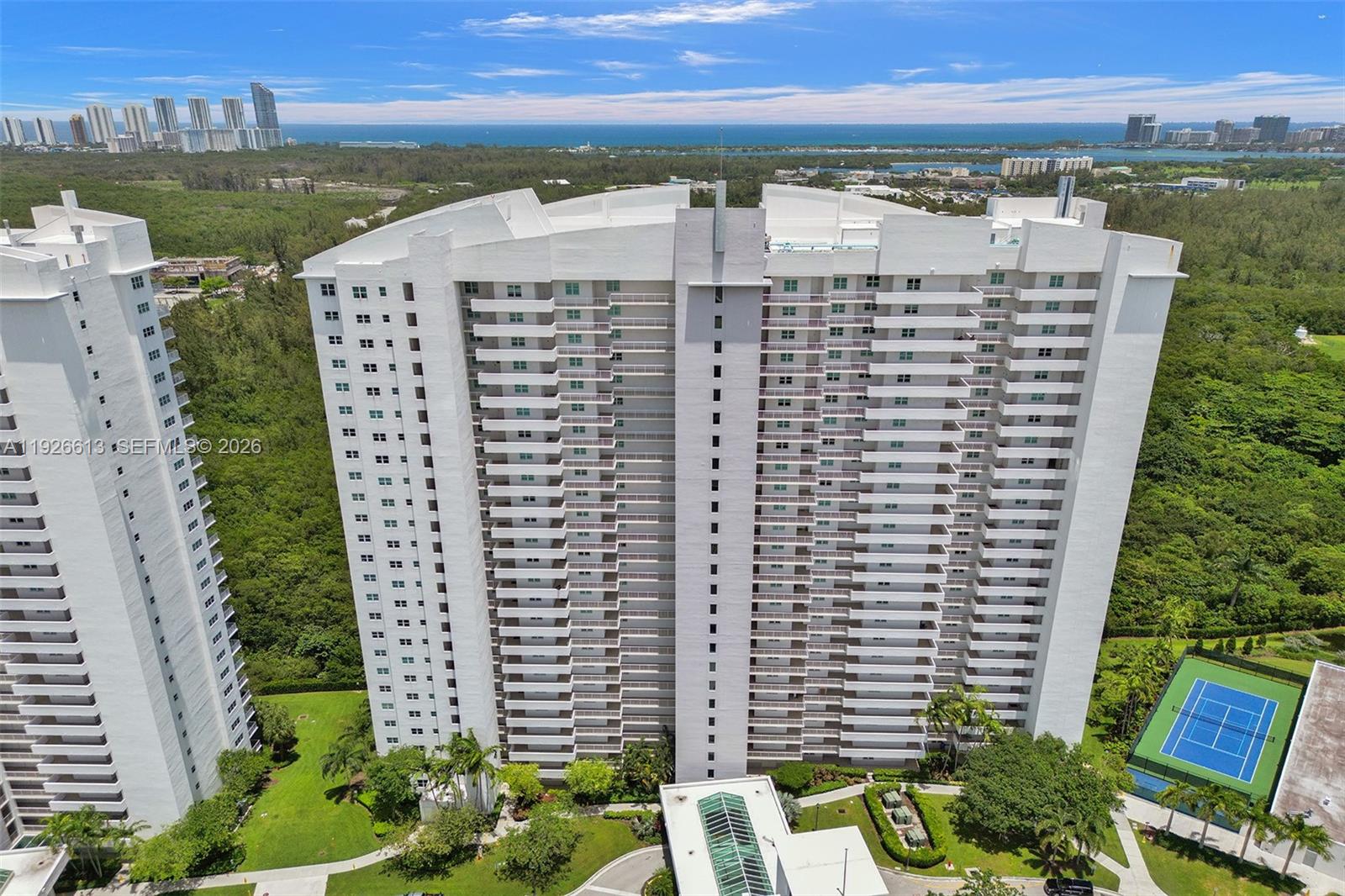 Rarely available penthouse corner residence offered for sale by its original owners! This spacious 2-bedroom, 2-bath plus den features soaring 12-ft ceilings and expansive skyline views of Sunny Isles Beach, Haulover, and Bay Harbor Islands. The layout feels grand and filled with natural light. Stone floors have just been polished, and both bedrooms feature brand-new Chevron-style engineered herringbone wood flooring. Dishwasher, microwave, and stovetop are brand new. This is the only line in the building with no windows facing the catwalk, offering enhanced privacy and additional windows, including a windowed foyer, all bathrooms, and extra windows in the primary bedroom. Thick hurricane-impact windows provide excellent sound insulation. Assigned covered parking conveniently located on the first level, with the option to rent a second space. A must-see penthouse. Building amenities include pool, gym, tennis court, playground, dog wash station, and high-speed internet/cable. Conveniently located near Costco, Target, Publix, new Mater Academy, UM Health, Pura Vida, Reserve Padel, and the beaches.