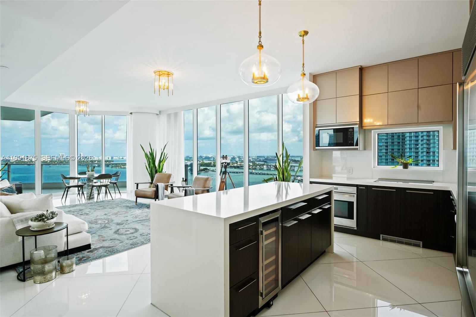 Arrive by private elevator to your personal foyer and step into a light-filled, glass-walled residence where the open kitchen, living, and dining areas immediately draw your eyes to the endless blue of Biscayne Bay. The main terrace showcases spectacular sweeping water views of the Bay, the Ocean, parks, the Port, Miami Beach, and the Islands, while the west balcony captures colorful sunsets and skyline views stretching toward Wynwood, the Design District, and Miami’s northwest neighborhoods. This designer 3-bedroom, 3.5-bath residence spans 2,201 SF and features en-suite bedrooms, walk-in closets, and spacious balconies—each with its own unique perspective of this tropical paradise. The highly sought-after 02 line includes impact glass walls and doors, two A/C zones with Nest thermostats, Somfy curtains and blackout shades, Sub-Zero refrigerator, Wolf built-in oven and cooktop, wine cooler, Lutron dimmer lighting, large-format white ceramic floors & a laundry storage room. The unit also includes one assigned garage space with EV charger and private elevator access.  Paramount Bay is a luxurious, established waterfront tower known for its high-fashion design, resort-style amenities, and serene atmosphere. Residents enjoy beautifully designed lobby spaces, pools, spa, sauna, fitness center, and common areas that are truly anything but ordinary—creating the feeling of a permanent vacation suspended above water, just moments from the best of Miami & the beaches.