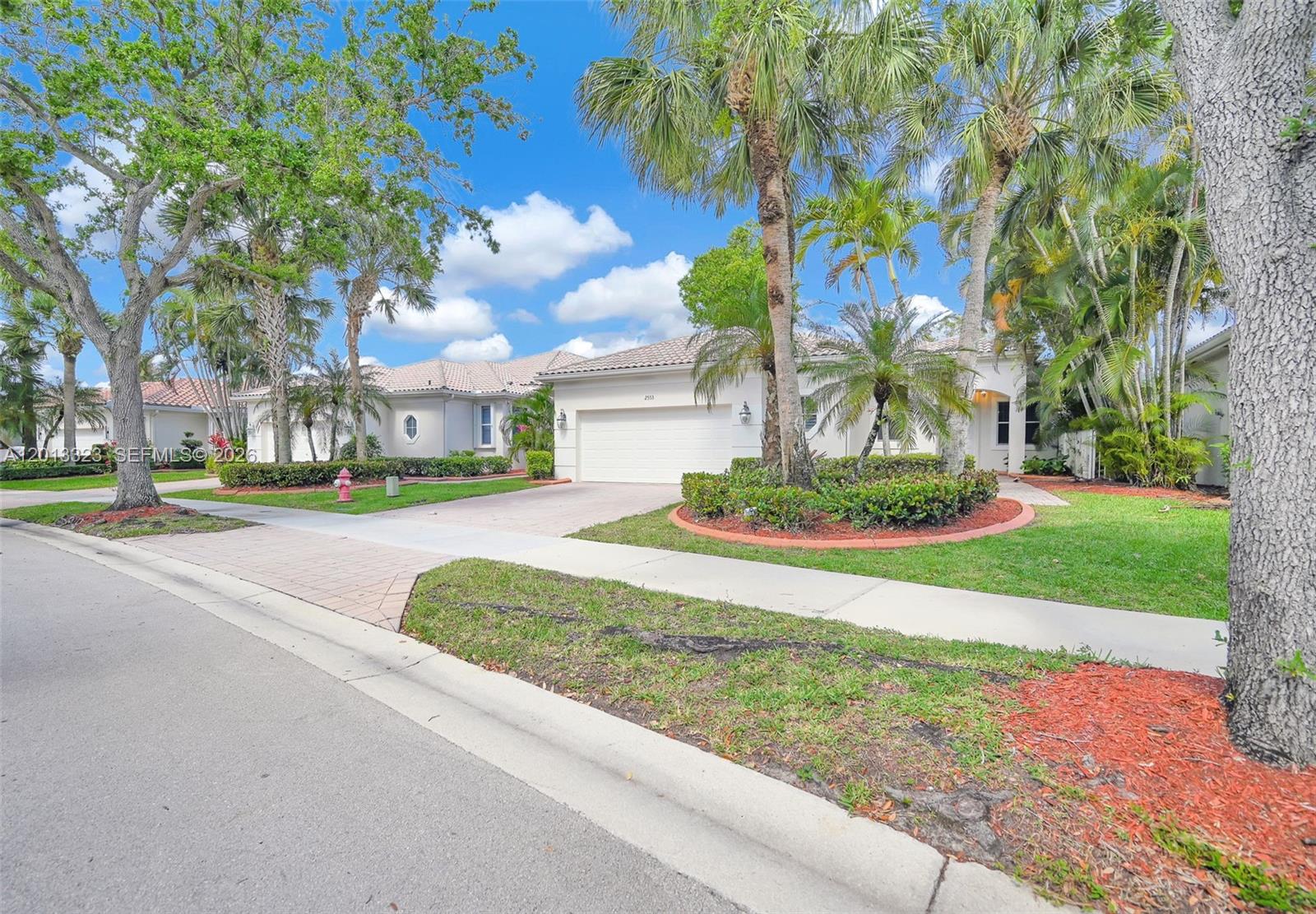 Stunning one-story waterfront residence in the gated enclave of Bay Pointe at Weston Hills. This 3BR/3BA home offers an open, light-filled layout with soaring ceilings and tranquil lake views. The kitchen features wood cabinetry, granite countertops, stainless steel appliances, and a breakfast nook. Main living areas showcase wood and tile flooring. The primary suite includes dual walk-in closets and a spa-like bath with soaking tub, shower, and dual vanities. One secondary bedroom is en-suite, ideal for guests. Enjoy breathtaking sunsets from the oversized screened patio overlooking a spacious, fenced backyard with room for a pool. Additional features include a large laundry room with sink and a 2-car garage. Resort-style amenities, top-rated schools, and prime access to I-75, dining, and parks.