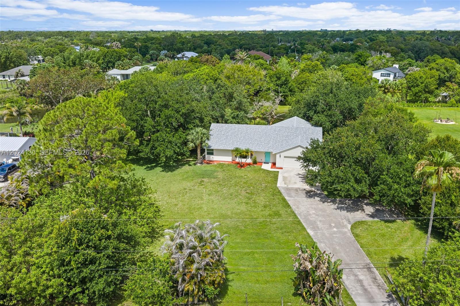 Jupiter Farms Oasis is waiting for you!!This 4/2 home sits on 1.25 acres with large pond. Offering the perfect balance of nature, privacy and convenience.  This home has an extra large multi use room with endless possibilities: a playroom, mother-in-law quarters, extra office space. The options are endless. The vaulted ceiling and skylights allow a natural glow to shine all the time. The primary suite has a gorgeous view of the pond and backyard birds. Besides the 2 car garage it has a shed for extra storage.  This residence has a new roof (2025), new A/C, new water filters system.  It has new siding and impact glass windows.  The garage door is also impact.  The large covered porch and patio overlook the pond and nature scape that will take your breath away. There is plenty of room for all the toys with No HOA. It has easy access to I95 and the turnpike and conveniently located close to the pristine Jupiter beaches, fine dining, parks and shopping.