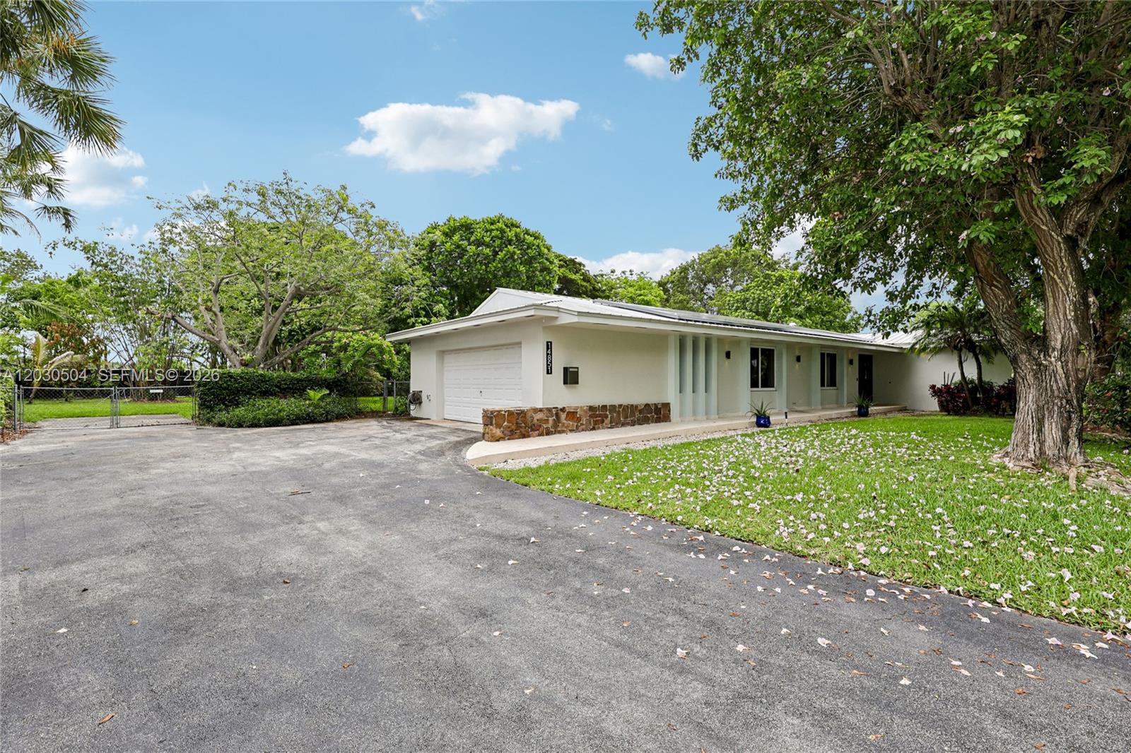 Welcome to effortless Florida living in one of South Miami-Dade's most sought-after communities. This charming single-story ranch sits on a beautifully landscaped lot surrounded by mature trees and tranquility that Palmetto Bay is known for. Step inside through a striking modern black double-door entry into a bright, open living and dining area and a warm, welcoming feel. The kitchen overlooks the pool through a large picture window and opens directly to the screened lanai — making indoor-outdoor living seamless from the moment you start your morning.
The true showstopper is the expansive screened pool enclosure featuring a kidney-shaped pool, spa, and travertine deck — an entertainer's dream ready for year-round enjoyment. Beyond the lanai, a generous, flat backyard with lush green grass  ample space to play, garden, or simply enjoy the Florida sunshine. Tropical landscaping give this home exceptional curb appeal, while the mature tree canopy provides natural shade and a serene setting that's hard to find at this price point. Located in top-rated Palmetto Bay with A-rated schools, close proximity to parks, dining, and easy access to US-1 — this is the Florida lifestyle at its best