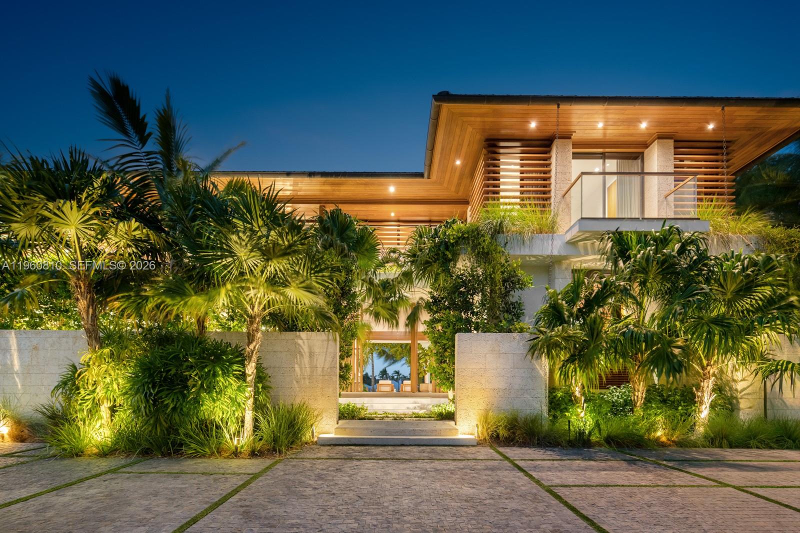 An architectural statement of modern waterfront elegance set within the private guard-gated enclave of Old Cutler Bay, this exceptional custom-built estate by renowned architect Cesar Molina showcases refined design and resort-inspired living. Framed by serene water features and lush tropical landscaping, the residence is defined by soaring volumes, expansive glass, and seamless indoor-outdoor integration, capturing tranquil water views while offering remarkable privacy.
The home features five bedrooms plus a separate guest suite, currently utilized as a private office, along with a dedicated cabana lounge and fully equipped home gym. The chef’s kitchen is appointed with custom Mia Cucina cabinetry and a signature Officine Gullo range, blending performance with timeless Italian craftsmanship. Crestron smart home automation, Lutron lighting, an integrated interior and exterior sound system, and a full-house generator provide effortless luxury and convenience.
Designed for elevated entertaining, the cabana lounge features a temperature-controlled wine wall, wine cellar, marble bar, and Officine Gullo built-in wine dispenser. Resort-style grounds showcase a summer kitchen with covered dining area, PebbleTec pool, putting green, and 180 feet of waterfront with Ipe dock with 200-amp electrical service, offering direct access to Biscayne Bay.