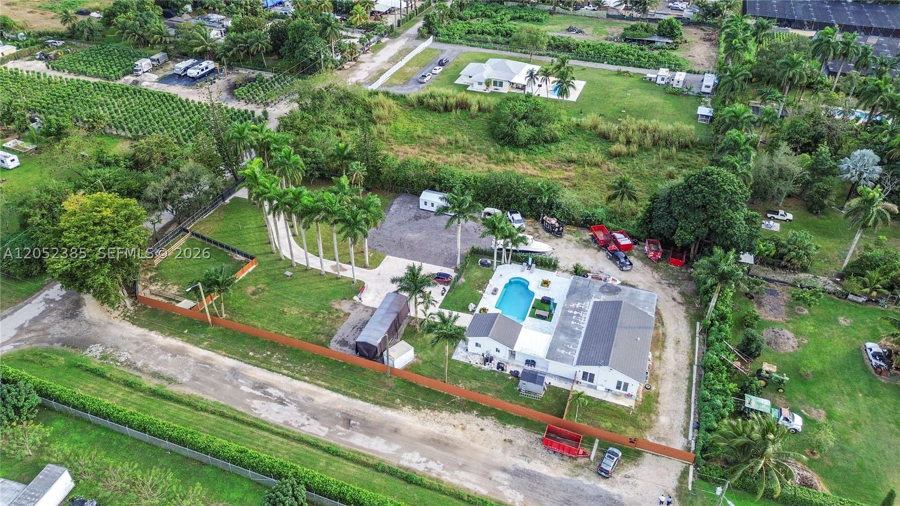 Welcome to your private Florida acreage retreat with a stunning palm-lined driveway and open-concept living. This beautifully finished home features porcelain tile throughout, a gourmet kitchen, and expansive living and dining areas. In total, 4 beds/4 baths, with 3 beds/3 baths in the main home. A separate mother-in-law/guest suite offers multigenerational living or rental income potential. Features: 2025 HVAC, 2022 Roof, Hurricane Impact Windows, Plumbing/Electrical 2022, and more!! Enjoy a sparkling pool and covered outdoor entertainment area. Fully fenced, offering privacy and security, and includes a separate farm area for small livestock, gardening, or hobby farming. No HOA—bring your toys, animals, and creativity. Only 25 minutes from Key Largo amenities. Live where others vacation!
