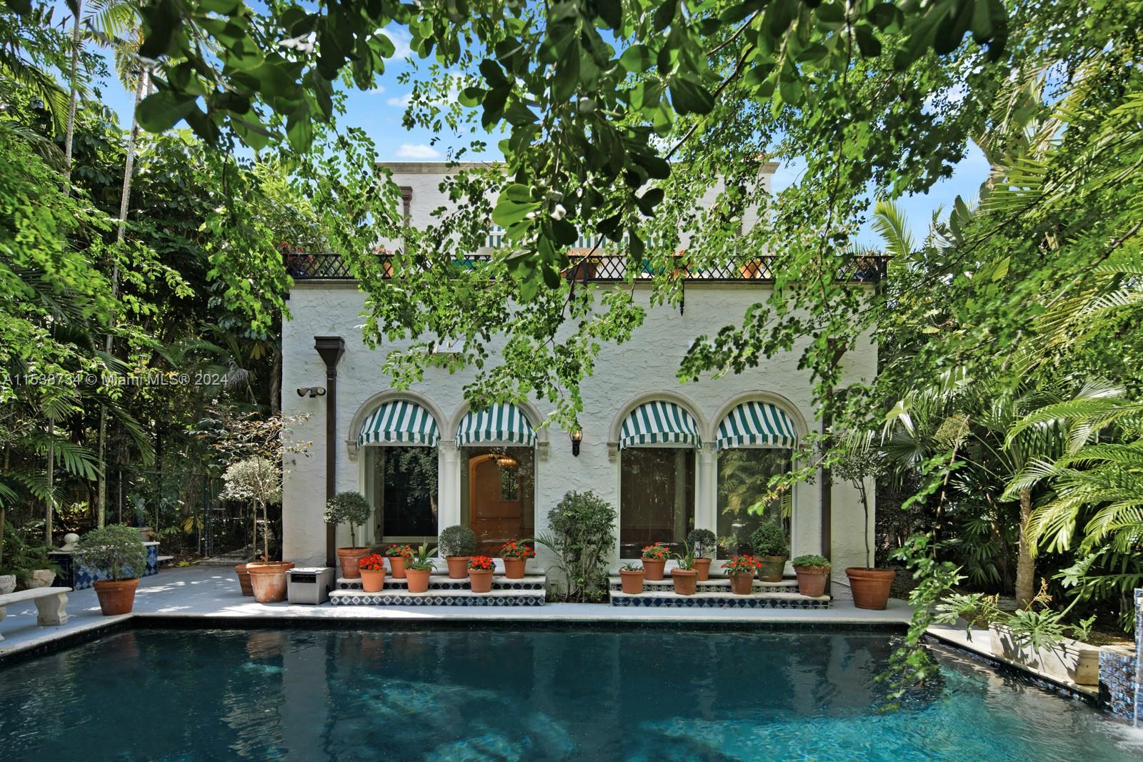 Explore this exceptional opportunity to own “Casa Diva”, a rare vintage Mediterranean-styled villa and one of South Coconut Grove’s most unique properties. This ultra-private estate is situated on a 21,000 sq ft lot with a 700 sq ft pool surrounded by 7 professionally landscaped tropical gardens. Inside, original Dade County pine floors lead to a grand living room with 11 ft ceilings, wood burning fireplace and adjoining sunroom. The formal dining room has an adjoining butler pantry, and the gourmet kitchen opens to a garden patio perfect for alfresco dining. Upstairs, the Primary Suite has a wood burning fireplace, luxurious bathroom with rainfall shower and steam, and private terrace overlooking the pool and grounds. Impact windows throughout, full home generator and multiple CC cameras.