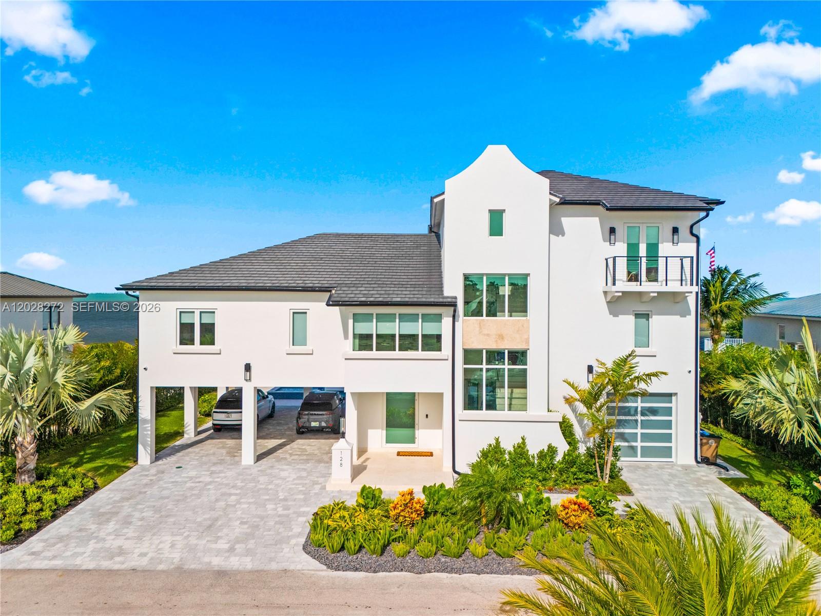 Experience the rare combination of protected dockage and direct oceanfront living at 128 Sunrise Drive. Situated within an exclusive gated enclave of just 20 lots, this newly constructed 2025 waterfront residence offers a level of privacy, luxury, and lifestyle rarely found in the Florida Keys. Positioned to capture unobstructed ocean views and a year-round ocean breeze, this home offers an elevated coastal lifestyle with exceptional attention to detail throughout. Each bedroom features a private ensuite bathroom and spacious walk-in closet, while a true foyer entry, elevator, and abundant storage create a floor plan that is as functional as it is beautiful. The open concept living offers the perfect home to entertain and enjoy tons of natural light. The interior design offers high end tile selections, designer light fixtures and wood accents throughout. The home also features 3 interior bars and window treatments throughout. The living spaces seamlessly transition outdoors, where an expansive entertainment area is designed to embrace the Keys lifestyle. Enjoy a resort-style pool and hot tub, outdoor kitchen, and multiple spaces to relax while overlooking the waters of the Atlantic. A rare wade-in beach offers effortless access to the ocean, while protected dockage on the canal side provides a secure spot for your boat. Additional features include a one-car garage, oversized air-conditioned storage space, and a generous covered carport ideal for vehicles, boats, and more!