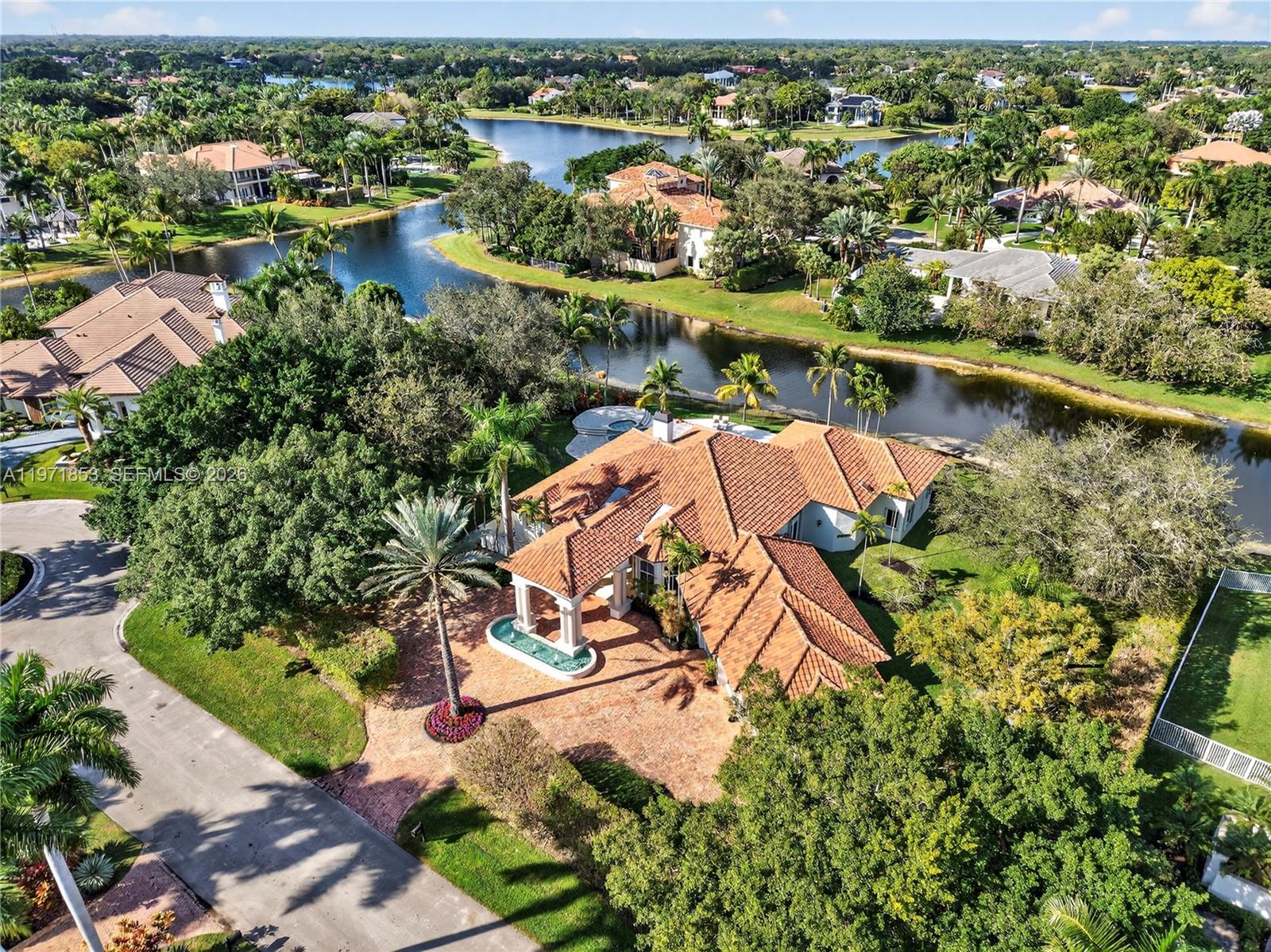 Experience refined living in Westons most prestigious guard gated community, Windmill Ranch Estates. From the moment you arrive, a grand fountain entrance sets the tone for the elegance that awaits you inside.A stately Porte Cochere provides both architectural distinction and convenient covered access, creating a dramatic first impression. Step through the large entrance doors to discover expansive living spaces designed for both luxurious entertaining and comfortable everyday living. Each of the 5 spacious bedrooms offer privacy and comfort, with beautiful appointed en suite bathrooms. There is also an additional library/ office with cherry wood floors and high ceilings.The primary suite serves as a private retreat, designed for relaxation and tranquility. The home features 2 fireplaces, adding warmth and ambience to formal and informal gathering areas alike.Soaring ceilings, abundant natural light, and refined finishes elevate every room. At the heart of the home is the gourmet kitchen which is a chefs dream appointed with high end appliances, custom cabinetry, generous counter space, and an ideal layout for hosting dinners and celebrations. outdoors your private oasis awaits. Enjoy year round Florida living with a resort style pool and spa, surrounded by lush landscaping and ample patio space for entertaining or unwinding in complete serenity. Once you experience your first sunset , you will be hooked.