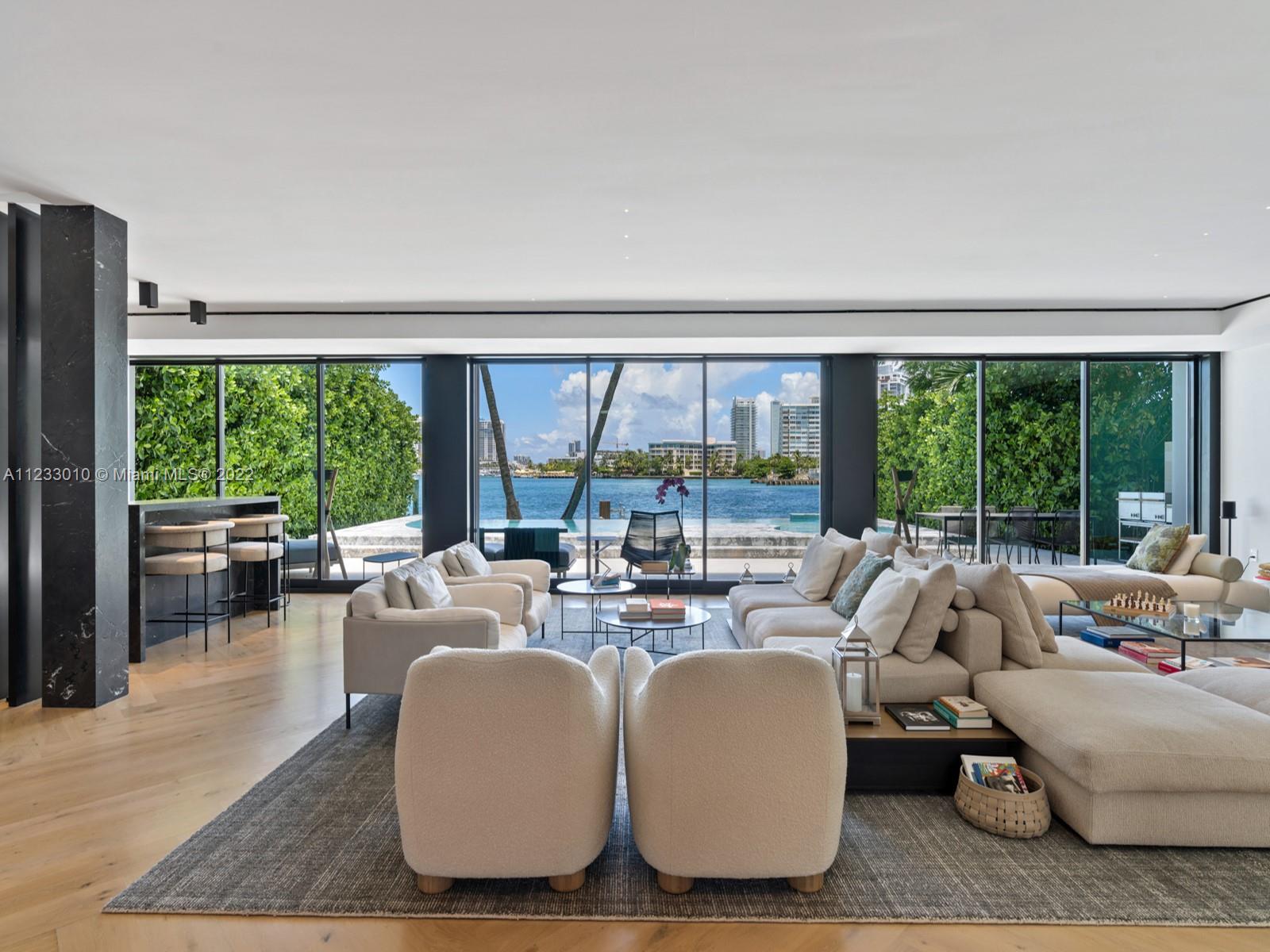 Completed in 2021, this resort-style contemporary home on Rivo Alto, the most desirable of Miami Beach’s Venetian Islands, is highlighted by a dramatic pool and spa, clad in Statuario marble and lined in transparent acrylic facing the fine Ipe wood dock and eastern Biscayne Bay views. Various expressive marbles highlight the open-plan living area, with its elegant cocktail bar, sweeping sculptural staircase, retracting glass doors, and masculine chef’s kitchen, well-equipped with Gaggenau appliances and mirrored Italian cabinetry. The home offers six bedrooms, a discreet staff suite, a lavish master bath by Boffi, a massive master closet, and a third-floor roof deck large enough to entertain in style, while streetside, lush landscaping enhances the drama of the entry approach.