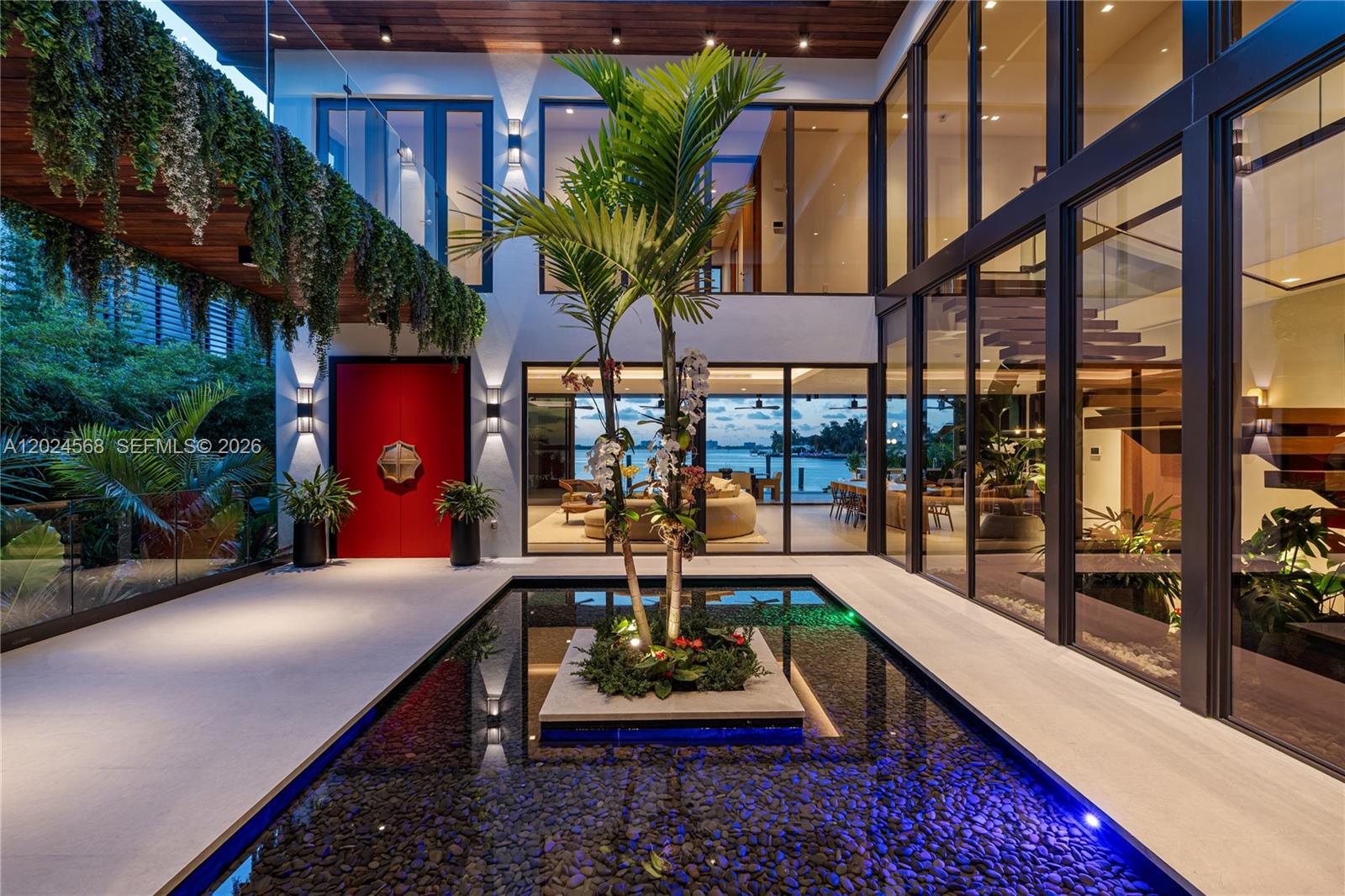 One of the most anticipated new construction waterfront residences completed in Miami Beach, Villa Ayana is a newly architectural masterpiece located in the exclusive gated community of Normandy Shores. Situated on an oversized 12,427 SF lot with 76 FT of waterfront and breathtaking open bay views, this private sanctuary offers a rare combination of luxury, tranquility and immersive tropical living. Inspired by a calming Bali-influenced aesthetic and refined French art de vivre, the residence was designed to create a true sense of escape. Lush mature tropical landscaping, soothing water features, interior garden and a spectacular open-air courtyard create a serene jungly atmosphere and rare calming zen ambiance throughout the property. Floor-to-ceiling glass walls seamlessly blend indoor and outdoor living spaces while flooding the interiors with natural light. The home features 7,428 SF of habitable space with 6 beds, 7.5 baths complemented by curated European materials and bespoke finishes throughout. Expansive terraces, a luxury spa-inspired pool with hot tub, summer kitchen and private dock complete the outdoor experience. The gated community offers access to the historic 18-hole normandy golf course originally opened in 1941 and tennis courts. Minutes from the beach, Bal Harbour and 25 minutes from South Beach, Villa Ayana represents a rare opportunity within one of Miami Beach’s fastest-evolving waterfront communities.