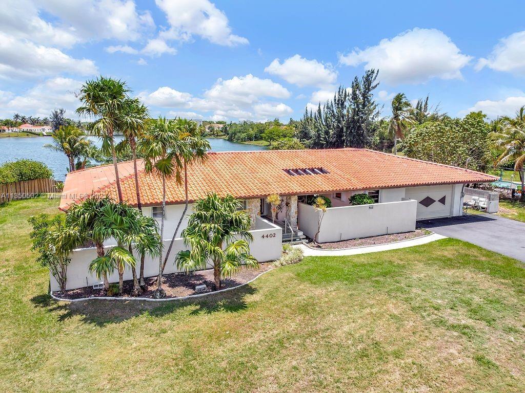Beautiful custom built 2760 sq ft home located on Blue Bird Lake. Large palm trees set the stage for this secluded 4 bedroom / 2 bath / 2 car home overlooking a panoramic lake view. A private paved driveway enters into the spacious .734 ac property. Triple split floorplan with barrel tile roof, atrium entry, game room, large screened-in porch. Kitchen has serving bar and looks out on lake and backyard patios. Hurricane shutters are included on all windows and doors. Close to restaurants, shopping, schools, and hospital. This home is the one you have been waiting for in a great location. This home is sold âs is needs some upgrades
