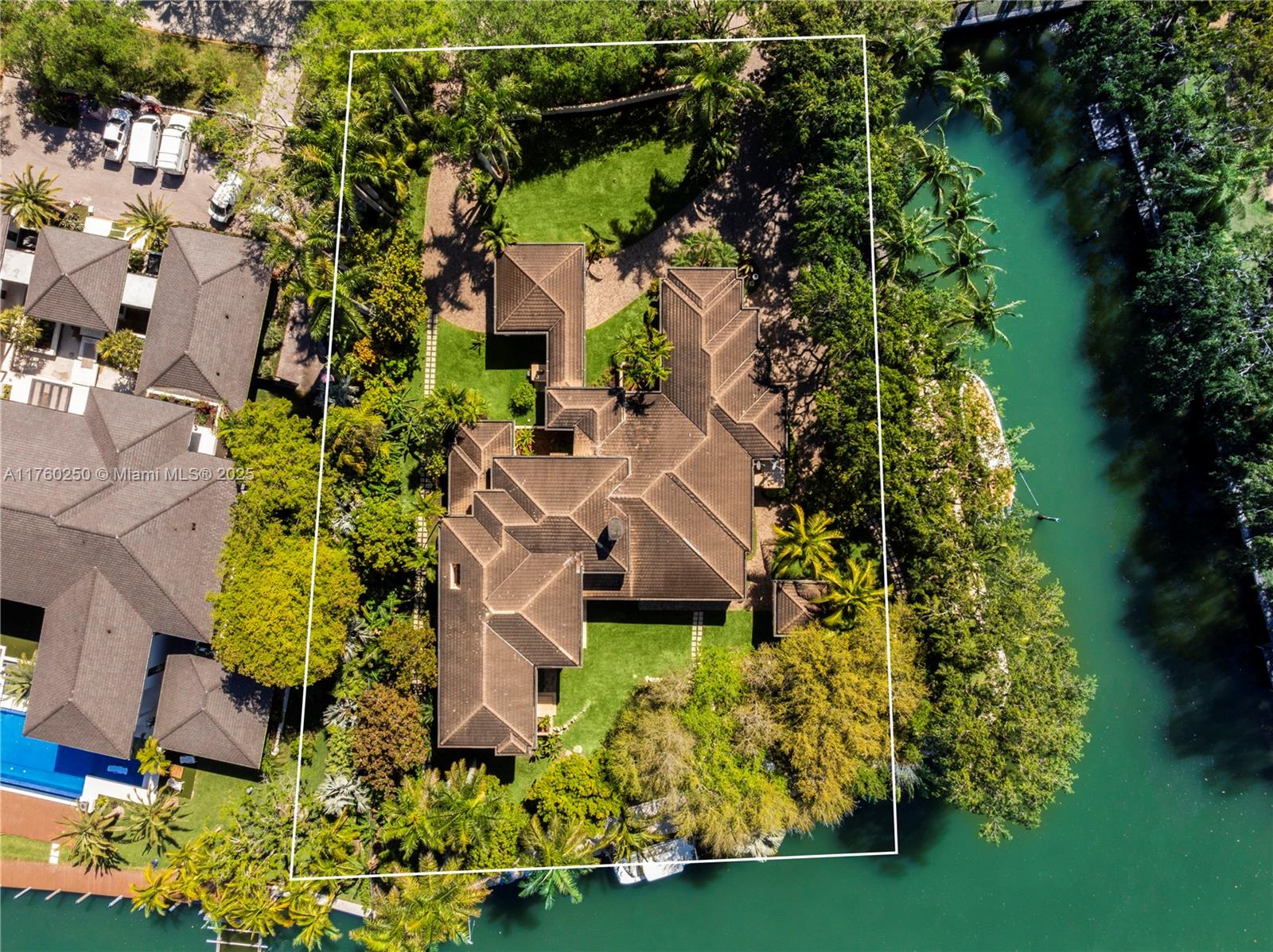 Designed by Barry Sugerman, this 7,698 SF waterfront estate in Gables Estates is a true masterpiece of elegance and modern luxury. Featuring 5 bedrooms, 7.5 bathrooms, the home showcases soaring wood-paneled ceilings, panoramic impact windows, and a grand stone fireplace. The custom open-concept kitchen boasts top-tier appliances, a marble island, and coffered ceilings. The principal suite has a private terrace with canal views, dual spa-like baths, and custom walk-in closets. Outdoors, enjoy stunning sunsets, over 400 ft. of water frontage, a private dock, 2 boat lifts, a shaded gazebo, covered terraces for alfresco dining, a cabana bath, lush landscaping and an included tennis membership. Complete with a home audio system, art lighting, and smart security, this is an architectural gem.