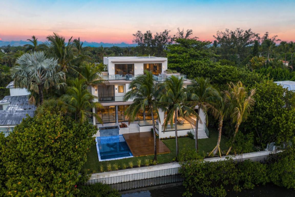 Welcome to 5 Barefoot Lane — a newly constructed, gated waterfront estate on Hypoluxo Island, where privacy is not just a feature, but the ultimate luxury. A bamboo-lined drive leads to stunning Intracoastal views across to the Manalapan estates. Boasting 82 feet of true deep-water frontage, complemented by a new elevated seawall, the home captures uninterrupted views across to the Manalapan oceanfront, offering a rare balance of openness and seclusion. Encompassing 6,511 square feet under air, the residence features a striking exterior of white coral stone, clean modern lines, and low-maintenance composite finishes. Inside, expansive living spaces showcase 48x48 Brazilian porcelain tile on the main level, a custom-built solid white oak staircase, and engineered white oak flooring through throughout the second and third floors. The chef's kitchen features Dolce Vita quartzite countertops, Thermador appliances, and Brizo fixtures.  Offering five ensuite bedrooms, plus a dedicated office and private gym, the home is designed for both comfort and functionality. The primary suite includes a spa-like bath & steam room with large-format porcelain tile, a refined modern aesthetic, and oversized his-and-her closets  Ideally located between Palm Beach, Delray Beach, and Boca Raton, this exceptional property offers convenient access to private airports, fine dining, and Worth Avenue-delivering a rare blend of luxury, privacy, and refined South Florida living.
