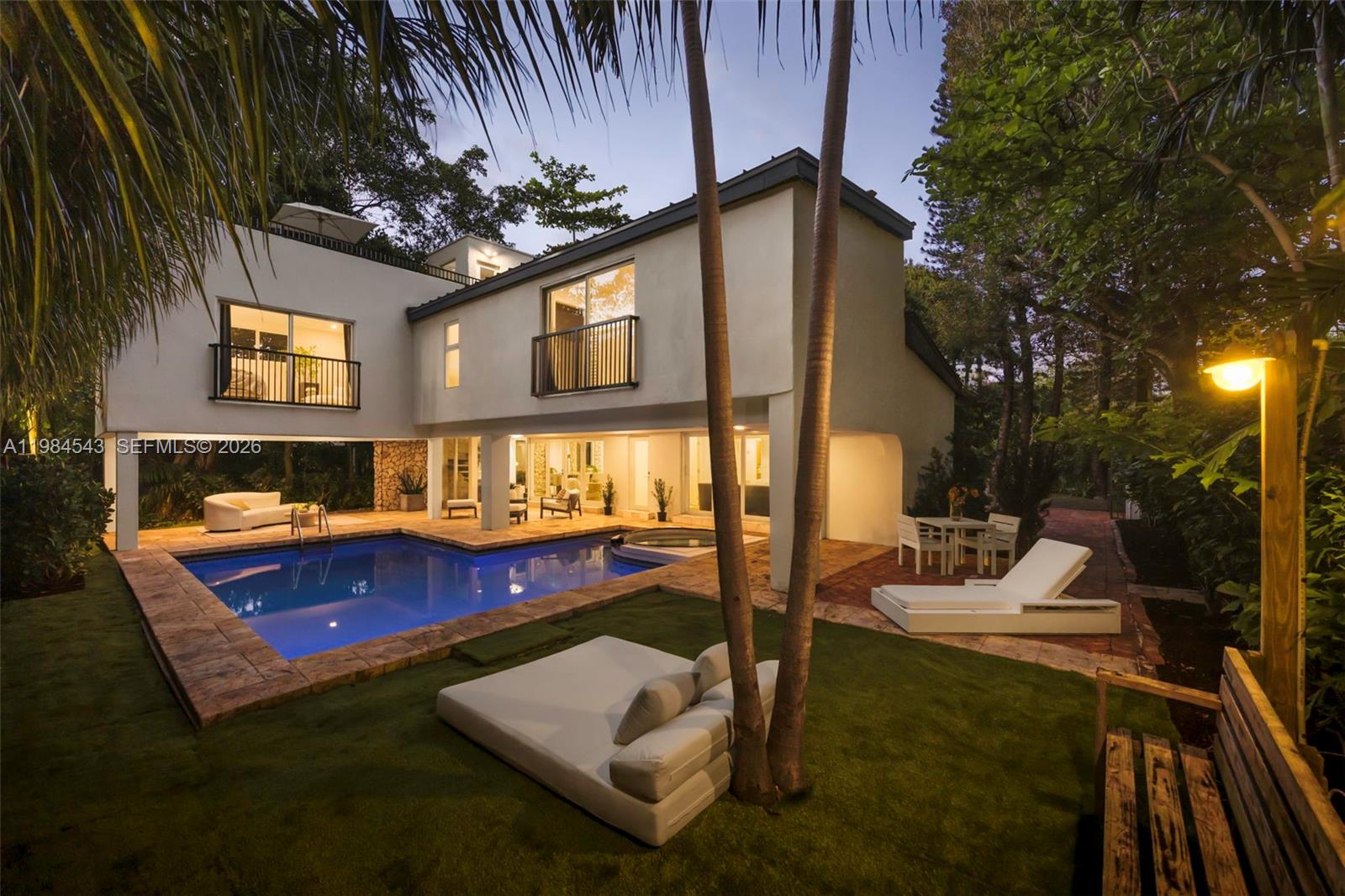 Thoughtfully remodeled mid-century residence on a prominent corner lot in North Coconut Grove, not in a flood zone, just minutes to top-rated public and private schools, parks, marinas, and the village. Gated 4BD/4BA with split layout: 2 bedrooms on the main level and 2 upstairs with ensuite baths. New 2025 metal roof and full impact glass complement wide plank European oak floors throughout. Light-filled interiors open to a spacious covered terrace for seamless indoor-outdoor living, ideal for al fresco dining and entertaining. Private backyard with pool, spa, lush canopy and fruit trees, plus rooftop retreat and timeless coral rock detailing.
