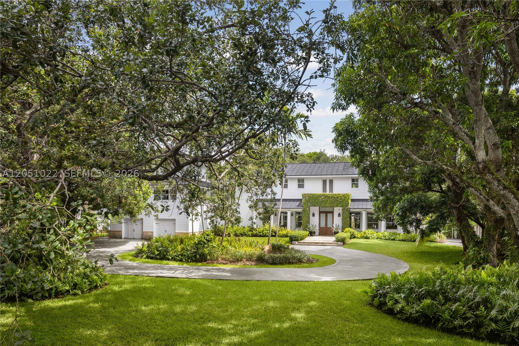 Set behind a gated circular drive and a magnificent mature oak, 6845 SW 98 Street captures the relaxed luxury of North Pinecrest living. Located on a lush, tree-canopied street, the home offers a warm, modern design with natural light pouring through every room. The main living spaces open seamlessly to two covered terraces, the pool, and surrounding gardens, creating an effortless indoor-outdoor flow.

The chef’s kitchen features vaulted wood-beam ceilings, white subway tile walls, Viking and Sub-Zero appliances, open shelving, a butler’s pantry, summer kitchen access, and distinctive black-and-white checkerboard marble flooring. The home also includes a spacious primary suite, multiple living areas, a gym, and a two-car garage. Upstairs, each bedroom opens to a private terrace overlooking the backyard, pool, and greenery.

Outdoors, enjoy a resort-style pool, expansive lawn, and multiple covered spaces designed for both entertaining and everyday living. This is North Pinecrest living at its best.