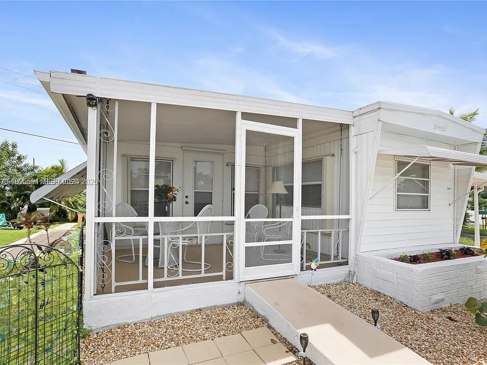Charming and fully furnished 3-bedroom, 2-bathroom manufactured home located in the 55+ Park City community in Davie. Brand new washer and dryer inside the unit. The yard has artificial turf for minimal maintenance, and there is a screened front porch with a pleasant view. A covered carport fits 2 vehicles. The property is located directly across from the clubhouse, which offers a pool and a putting green, including a mini golf course with artificial turf. It is conveniently close to highways, shopping, the airport, and the hospital.
You OWN the land — NO land lease. Low-maintenance - $77 monthly, move-in ready!