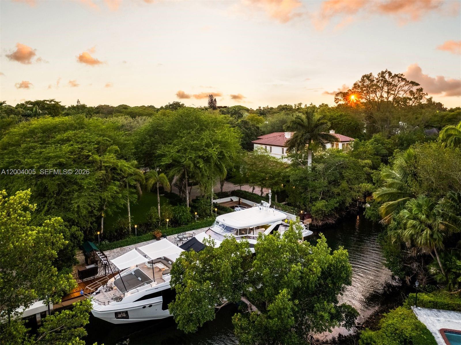 Situated in the exclusive gated community of Cocoplum Phase 1, with 24-hour Coral Gables police protection and resident tennis courts, this Italian villa-inspired waterfront estate by architect Ramon Pacheco offers 8,695 total SF on nearly one Acre lot, with 6 bedrooms, 7 full and 1 half baths. Built on pilings with high elevation, this immaculate single-owner gem showcases ~14-ft ceilings, grand proportions, elevator-ready design, four A/C units, A/C-equipped garage, and a Sony integrated audio system. A striking Mediterranean façade with triple-arched portico, classical columns, and an ornate iron-and-glass entry sets the tone. Lush grounds with 28 mature oak hammocks frame a circular driveway and expansive outdoor living. Enjoy direct ocean access with no bridges to Biscayne Bay, featuring a 100-ft seawall, additional 70-ft dock, and grandfathered 40-ft slip. The keystone marina deck, pool with waterfall spa, cabana, covered terraces, and summer kitchen create a resort-style setting. Interiors feature a dramatic triple-height foyer, marble staircase, refined millwork, and marble and wood floors. The gourmet kitchen offers custom Italian cabinetry, quartz counters, premium appliances, and wine storage. The expansive primary suite offers a private office, vaulted ceilings, and a spa-inspired bath with bespoke finishes and custom walk-in closets—delivering a refined private retreat within this exceptional waterfront residence.