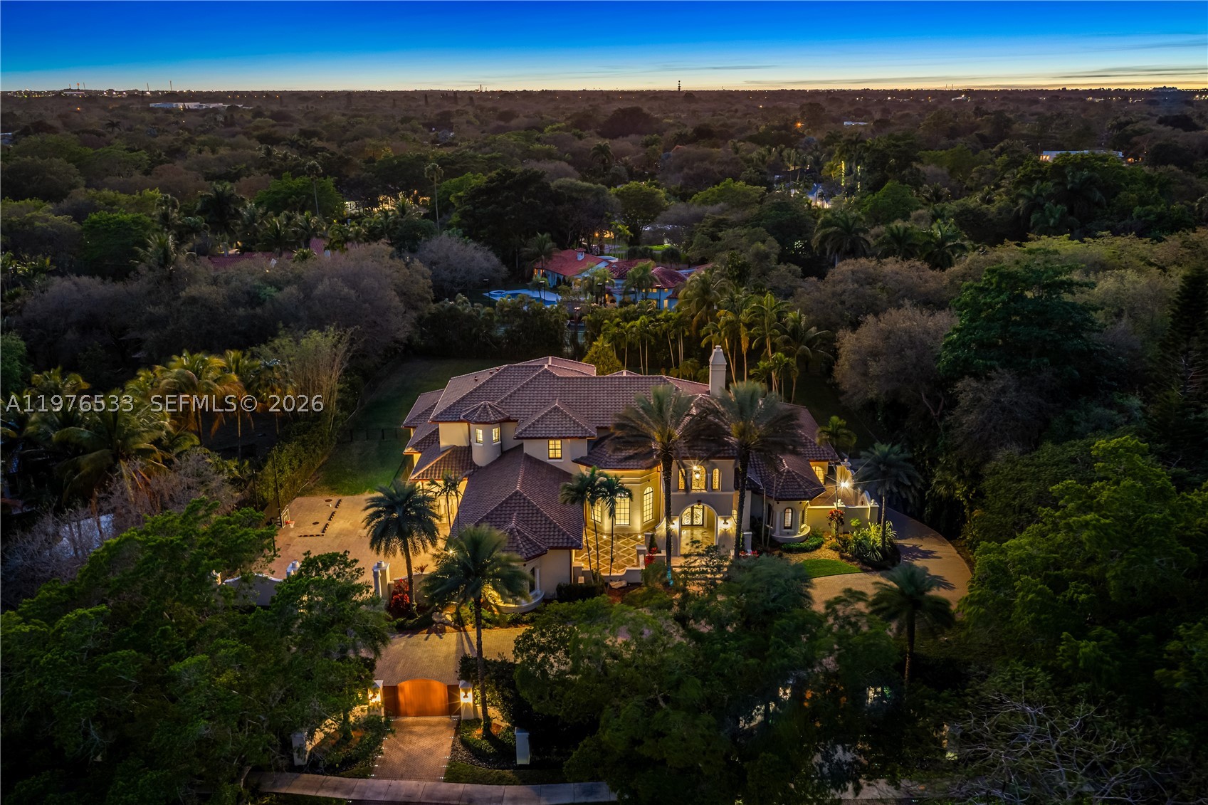 Perfectly located in the heart of Pinecrest along one of its most desirable corridors, this gated estate is tucked away on a lush acre-plus lot, offering privacy and convenience just minutes from top schools, parks, and the best of Miami living. Designed for comfort, entertaining, and effortless luxury, the residence features 7 bedrooms plus a private office, including a sumptuous primary suite on the ground floor overlooking the pool with soaring ceilings, designer lighting, and two oversized walk-in closets. The marble primary bath offers a soaking tub, an oversized shower ready for a steam system, and refined finishes.  At the center of the home, the chef’s kitchen is equipped with Thermador refrigeration, gas range, double ovens, hidden pantry, and breakfast nook. The kitchen flows into a spacious great room with fully retractable doors, seamlessly blending indoor and outdoor living. Entertainment spaces include a game room with full bar and cabana bath, temperature-controlled wine cellar, and multiple laundry areas.The home is fully wired for centralized audio/video control with LED lighting and Hunter Douglas blinds throughout, while a striking cylindrical elevator connects the levels. Car collectors will appreciate the three-car garage with lifts accommodating up to six vehicles. Outdoors, enjoy a heated saltwater pool finished in dark blue glass, propane fireplace, twilight landscape lighting, and expansive grounds. New roof - 01/26. Generous setbacks for privacy.