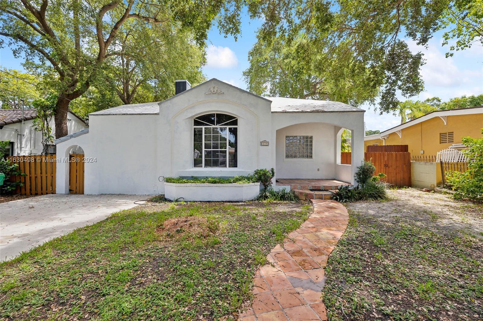 This charming 2-bedroom, 2-bathroom home located in the desirable The Roads. Built in 1938, this one-story residence exudes vintage charm with its original hardwood floors and classic tile throughout, offering a warm and inviting atmosphere reminiscent of a bygone era.
As you enter, you'll be welcomed by high ceilings in the living room, filled with natural light and centered around a cozy fireplace. The home features a family room and a versatile den/office room, perfect for working from home or creating your own personal retreat. The den/office room boasts an abundance of natural light and overlooks the serene backyard. The fenced-in backyard is a gardener's paradise, shaded by mature fruit trees and adorned with unique staghorn ferns hanging from the branches.