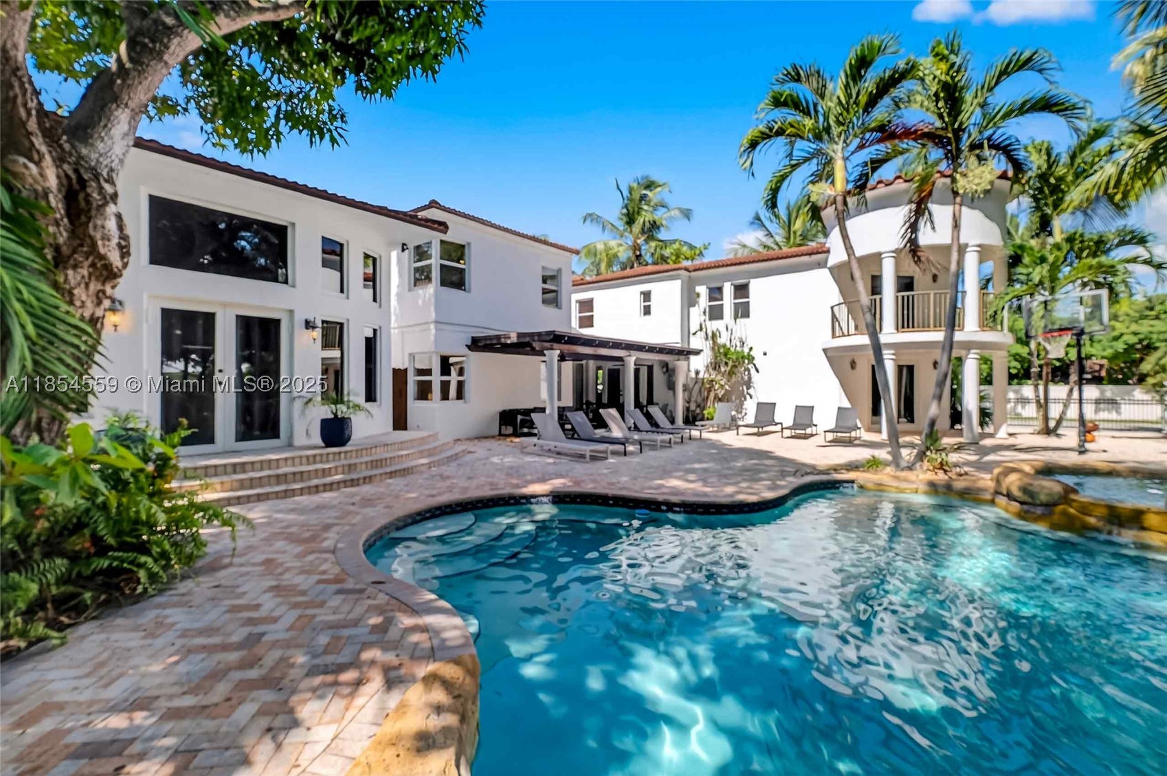 Experience exceptional waterfront living in this impressive 6,200+ sq ft estate, perfectly positioned on a sprawling 17,000+ sq ft corner lot with approximately 70 feet of canal frontage, a private dock, and no fixed bridges to Biscayne Bay and the Atlantic Ocean. Designed for those who appreciate space, privacy, and the boating lifestyle, the home features 7 bedrooms, 5 full baths, and 2 half baths, expansive living and entertaining areas, a resort-style pool surrounded by lush tropical landscaping, and a private theater. The luxurious primary suite is its own private retreat with a dedicated office, dual walk-in closets, two spa-inspired baths, and direct access to the pool and waterfront. A dramatic foyer with terrazzo floors, a fireplace, and an elegant staircase creates a memorable first impression, while the flexible floor plan offers 4 bedrooms on the main level and 3 upstairs. Currently licensed for short-term rentals with a proven performance history, this property offers a rare combination of luxury living, boating access, and income potential. Explore the immersive 3D Matterport tour and cinematic drone video to fully appreciate everything this exceptional waterfront estate has to offer. Images may be virtually staged and/or digitally enhanced (including furniture, colors, fixtures, landscaping, and décor) for illustrative purposes only.