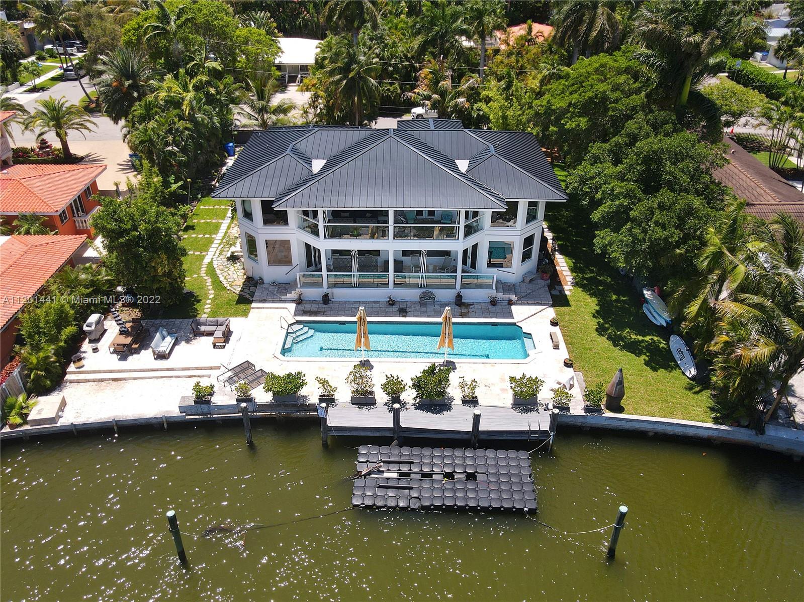 Attention boaters. This grand 7 bedroom, 5 bathroom, modern masterpiece sits on a 17,717 sf lot with 120' on the deep water, just 500 feet in from the wide bay with wide water views. Living area 4,400 sf as per owner. Enter the front gates to a huge car park, 2 car garage, and an impressive 2 story home with a new metal roof, impact windows and doors, new a/c, white porcelain tile throughout, volume ceilings, large Italian kitchen with DACOR appliances, large stacked back porches to enjoy the water views, waterfront pool and dock. Home has Volume ceilings, second floor family room, and  French doors that open to a huge master suite with glass walls bringing the expansive views to you. Bring your fussiest buyers.