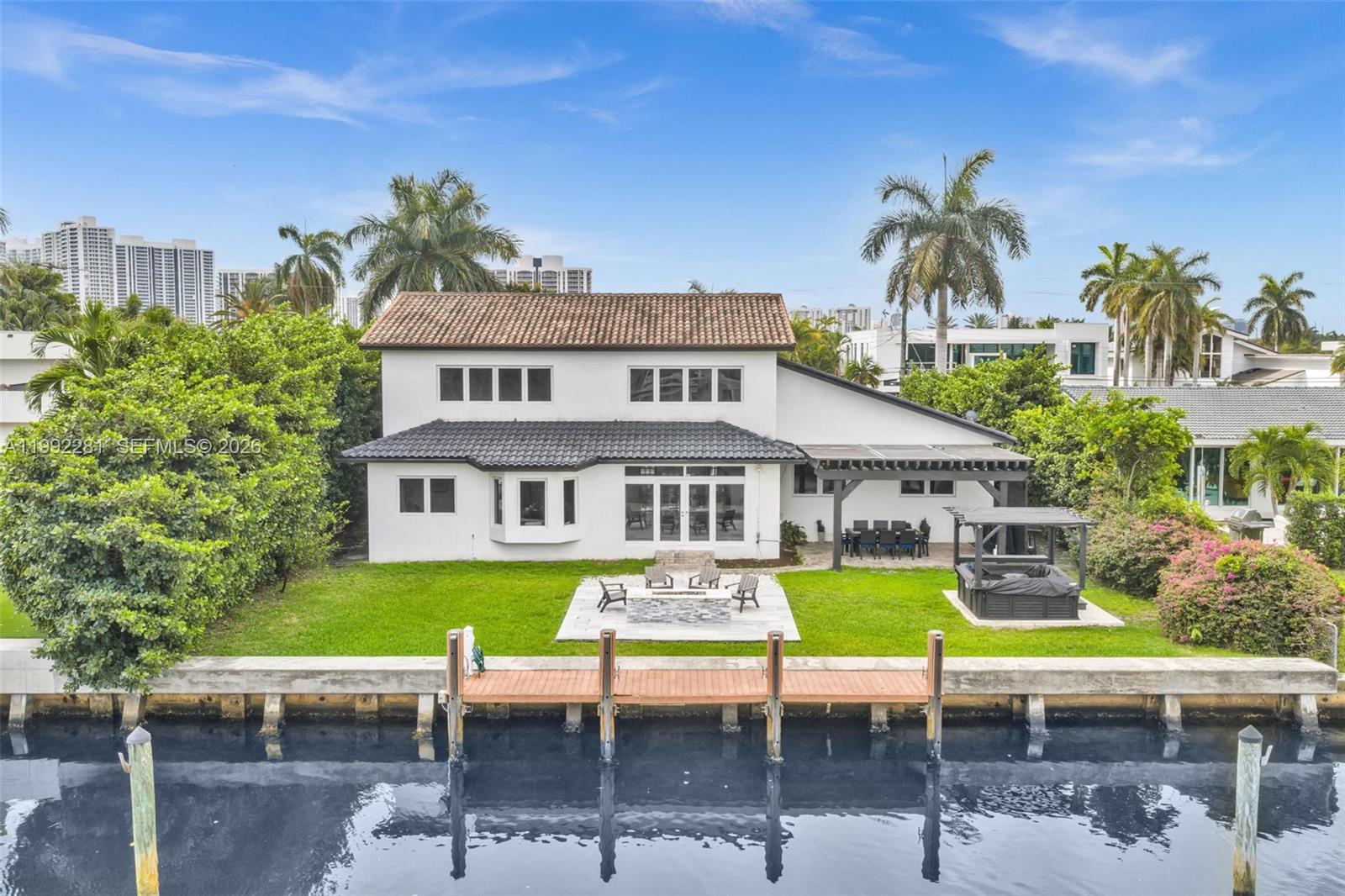 Located in the prestigious Golden Isles waterfront community, this exceptional estate offers 85’ of deepwater frontage with no fixed bridges and direct ocean access. Designed for both comfort and entertaining, this expansive 7-bedroom, 5-bath residence features a functional layout with two primary suites, spacious living areas, and an open-concept kitchen. Marble and wood flooring, impact windows, and multiple A/C zones enhance both style and efficiency. A private courtyard-style entrance welcomes you with a resort-style pool, while the backyard showcases a jacuzzi, fire pit, and stunning water views creating the ultimate outdoor experience. Boaters will appreciate the updated seawall and composite dock. Currently utilized as a successful short-term rental, this home offers excellent income potential. Additional features include a service/nanny’s room, oversized garage, circular driveway, and ample storage throughout. Ideally located just minutes from the beach, shopping, dining, and major highways, this home offers the best of South Florida waterfront living in one of the area’s most sought-after communities.