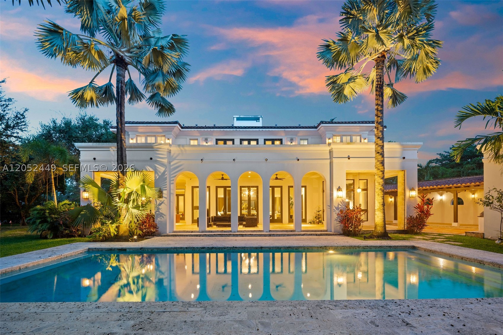 Exceptional one-owner tropical estate designed by architect George Hernandez, offering 6 bedrooms and 6.5 bathrooms on impeccably landscaped grounds surrounded by mature palms and specimen trees. Enter through one of four gated entrances to a grand paver motor court and striking arched entry. Light-filled interiors feature dramatic volume ceilings, expansive windows, custom millwork, designer finishes, natural stone throughout, and beautifully designed breezeways that create a seamless indoor-outdoor connection.
The chef’s kitchen offers premium appliances, custom cabinetry, an oversized stone island, and a sunlit breakfast area. Spacious family and entertaining areas flow effortlessly to the outdoor living spaces.
The expansive primary suite features hardwood flooring, oversized walk-in closets, and a spa-inspired bath. All secondary bedrooms are generously sized with large closets.
Resort-style amenities include a sparkling pool, covered terraces, summer kitchen, outdoor dining and lounge areas, private putting green, full basketball court, landscape lighting, and lush tropical gardens.
A detached three-car garage includes a cabana bath and separate guest/in-law quarters. Thoughtfully designed for entertaining and everyday living, this residence combines timeless architecture, outstanding craftsmanship, and luxury living.