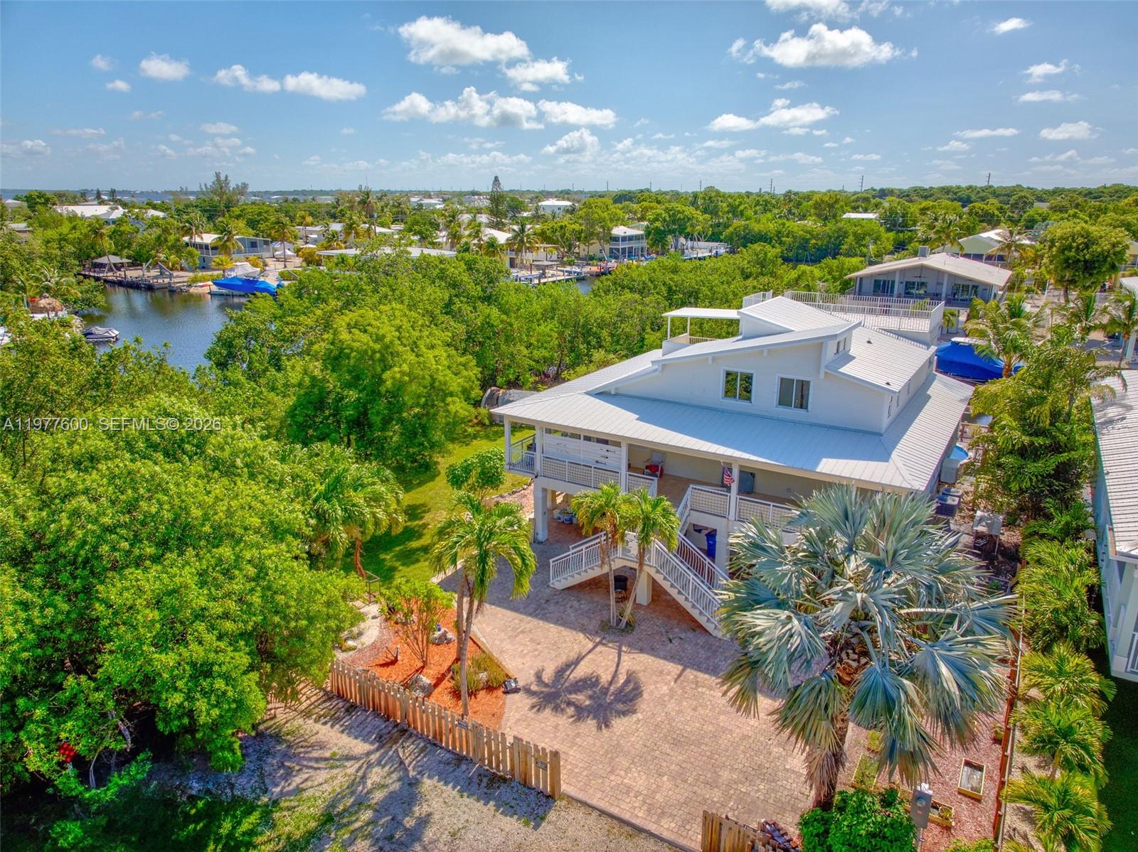 "UPDATES" 3/15/26 Freshly painted exterior, new pergola for relaxing on the dock, new fence, and new pool heater/chiller. Embrace the open bright treehouse feel of this renovated home tucked away on a dead-end street in sought after Twin Lakes subdivision. 40 minutes from Miami yet feeling like a tropical Oasis. Catch the breeze from the wrap around porches or the sunset from the large rooftop patio with a view of Blackwater Sound. The 65' Trex dock can be home to your boat, ski's and other water toys on the deep and wide canal. From the vaulted ceilings, beautiful eucalyptus flooring, large master suite, whole house Generac generator you will feel like you are on vacation every day. The salt water above ground pool surrounded by a Trex deck is easy to care for and is wonderful to relax in after a day of boating.